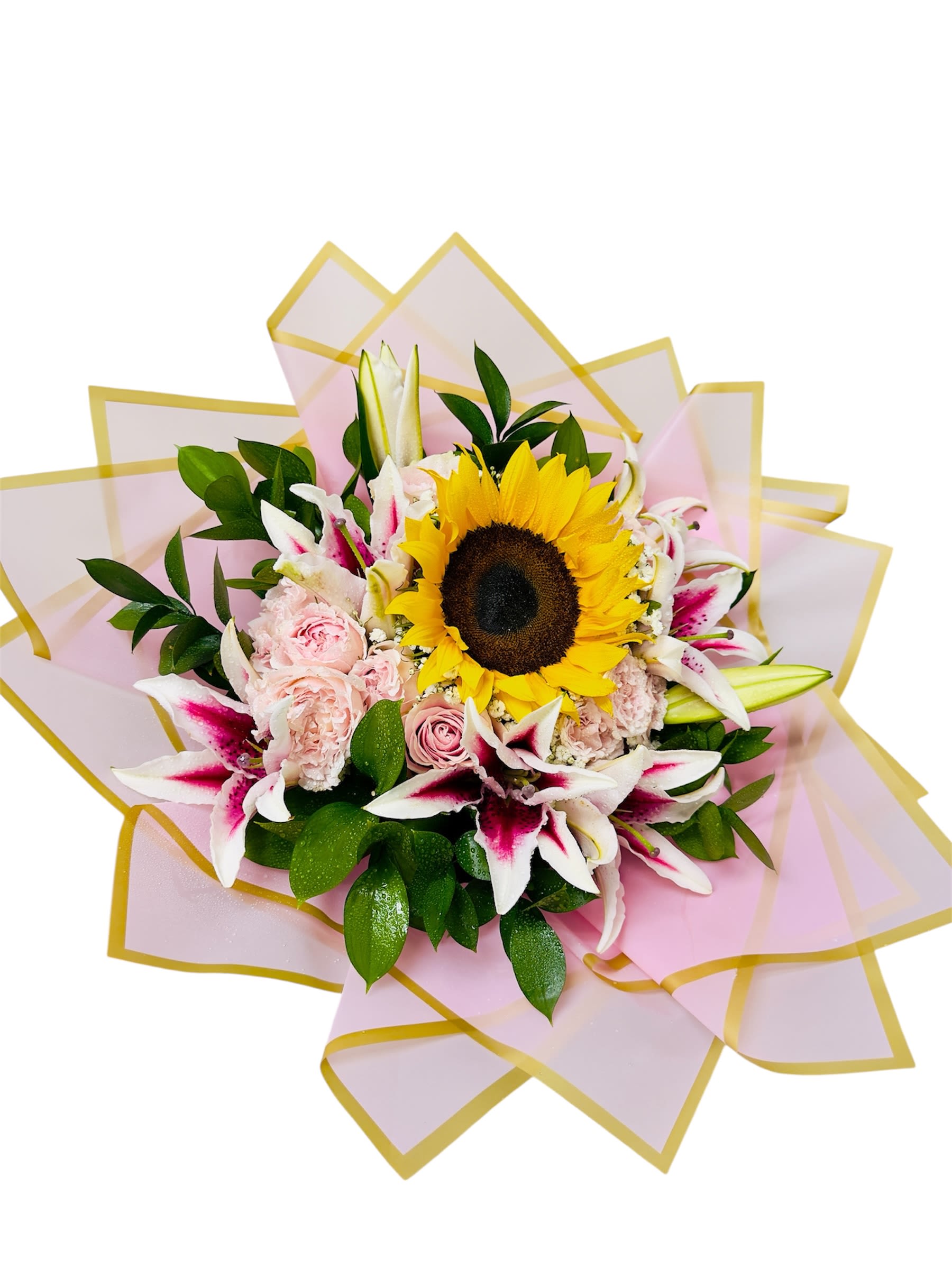 Golden Bloom Embrace  - This radiant bouquet captures warmth and tenderness in a luxurious blend of floral hues. A brilliant sunflower anchors the arrangement, symbolizing joy and positivity, while blush pink roses and carnations add romantic softness. White lilies with flushed pink centers introduce elegance, all wrapped in shimmering pink paper with a gold border—like a hug wrapped in sunlight. It's a versatile and uplifting piece, ideal for celebrations, tokens of appreciation, or moments when words simply aren't enough.
