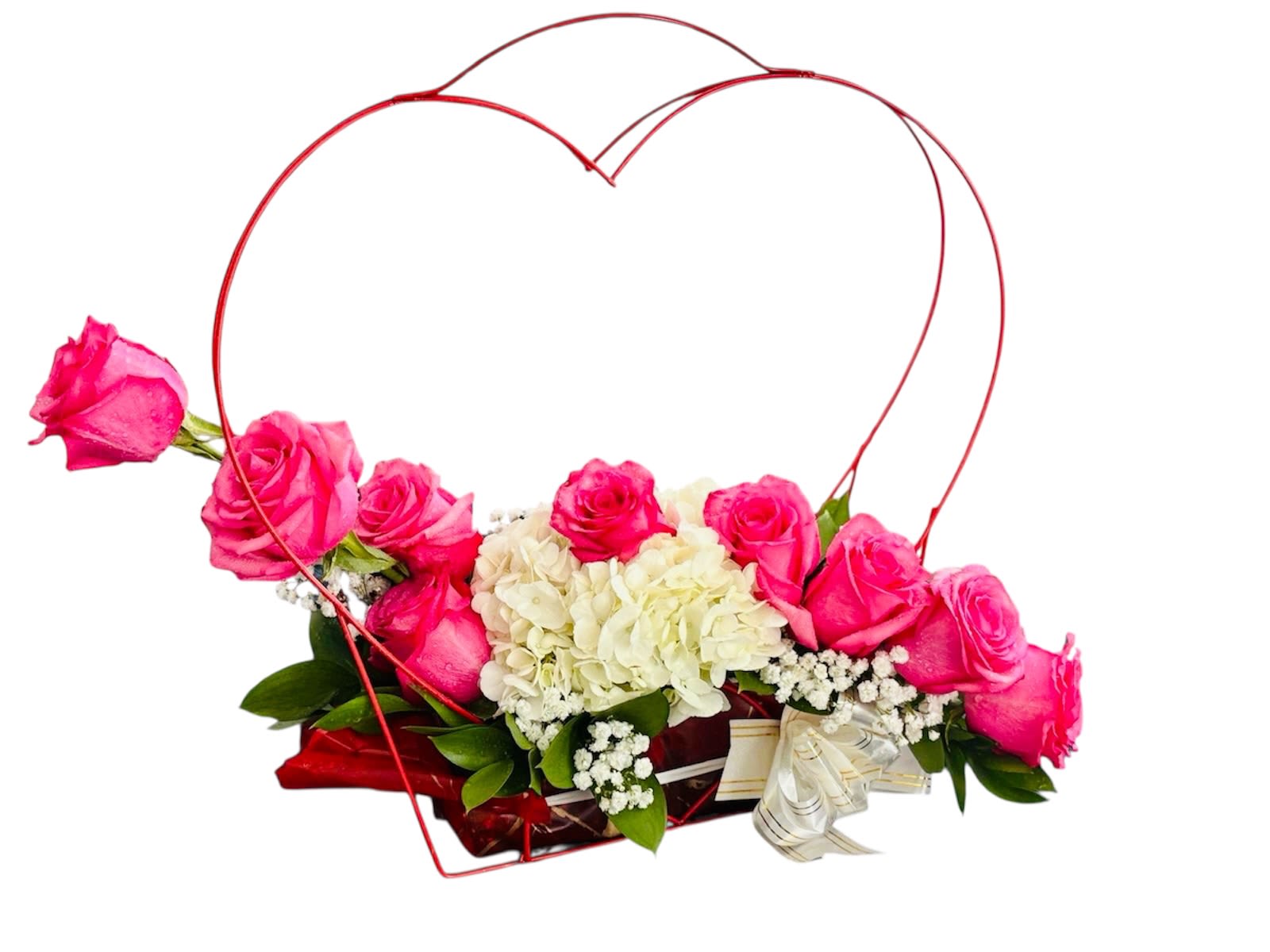Heartfelt Bloom  - This romantic and elegantly crafted arrangement speaks the language of love through its thoughtful composition. Soft pink roses and pristine white hydrangeas nestle inside a striking red heart-shaped wire frame, symbolizing affection and devotion. Baby’s breath and lush greenery add airy charm, while the white ribbon with golden accents at the base ties the design together like a beautifully wrapped sentiment. It's a perfect centerpiece for romantic gestures, anniversaries, or heartfelt celebrations.