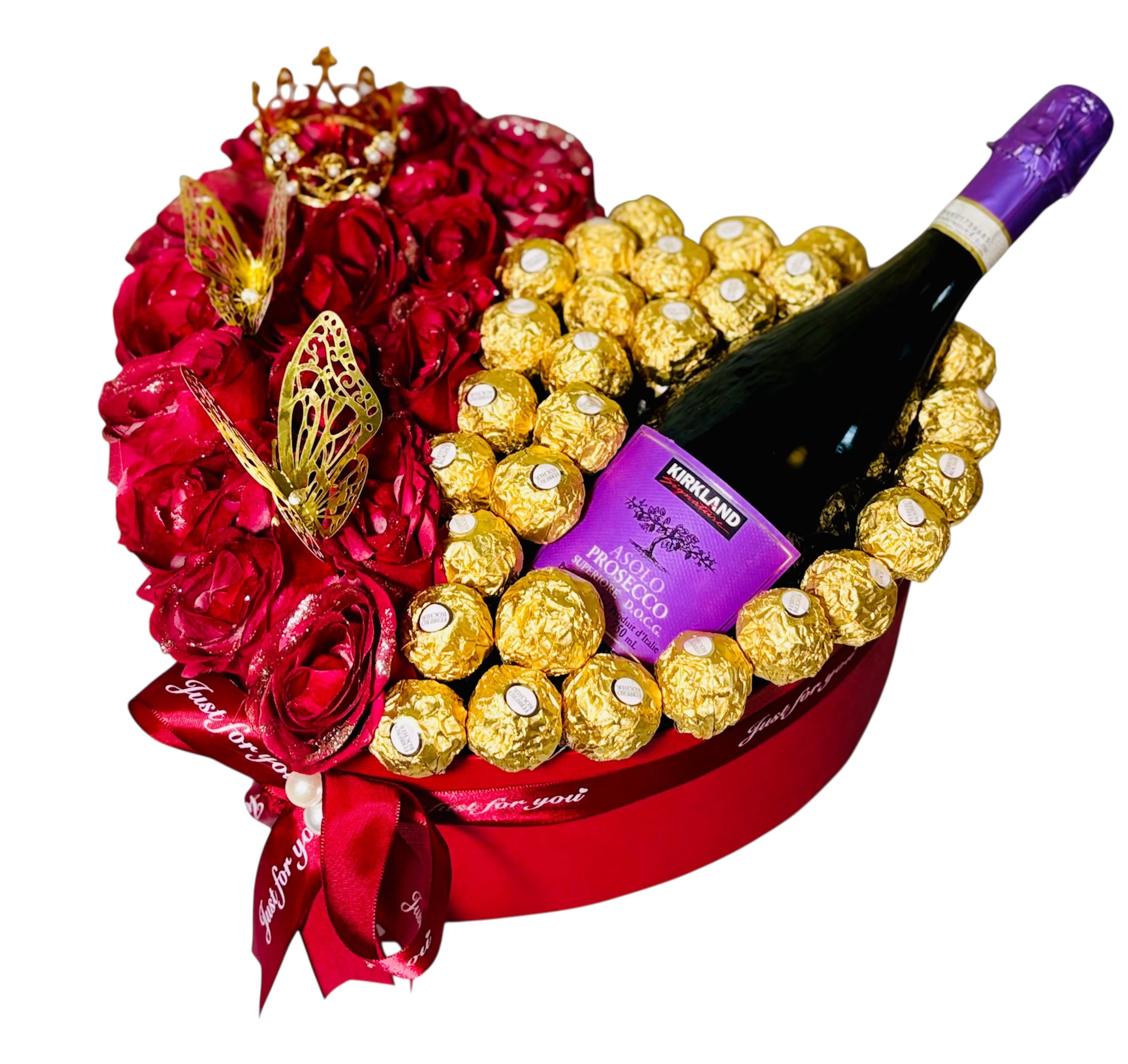Regal Indulgence - This luxurious heart-shaped gift arrangement is a stunning marriage of elegance and indulgence. The left side bursts with passion, featuring rich red roses crowned with golden butterflies and a delicate miniature crown—symbols of romance and royalty. The right half dazzles with golden Ferrero Rocher chocolates encircling a bottle of Kirkland Asolo Prosecco Superiore, hinting at celebration and refinement. A bold red ribbon reading *“Just for you!”* ties it all together, making this an unforgettable gift for Valentine’s Day, anniversaries, or any moment meant to feel truly special.
