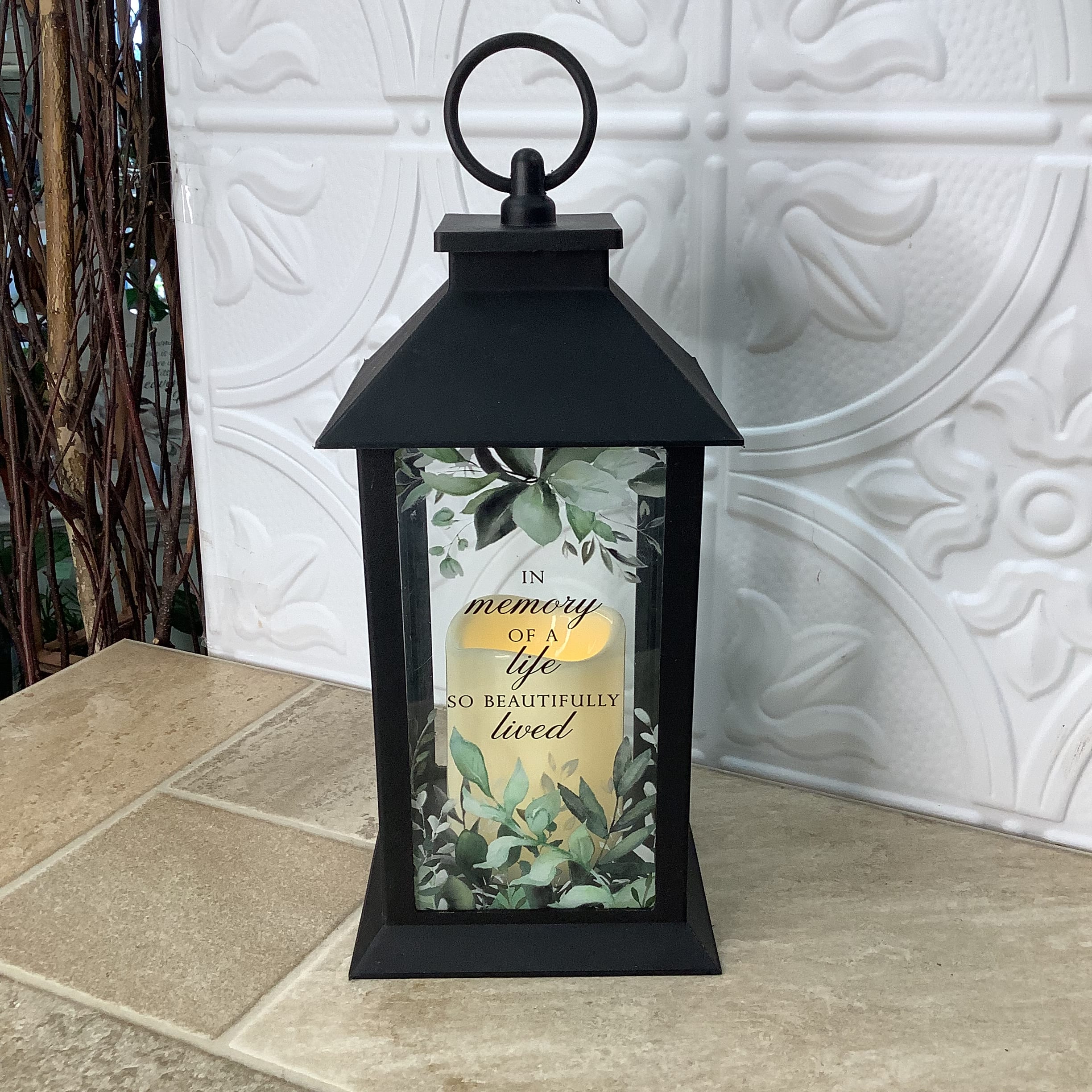 Lantern - In Memory Lantern - In Memory - This lovely lantern provides the perfect way to remember someone special to you. The led candle is encased in black metal and features the verse - In memory of a life so beautifully lived. It measures 5.5” x 5.5” x 12” tall