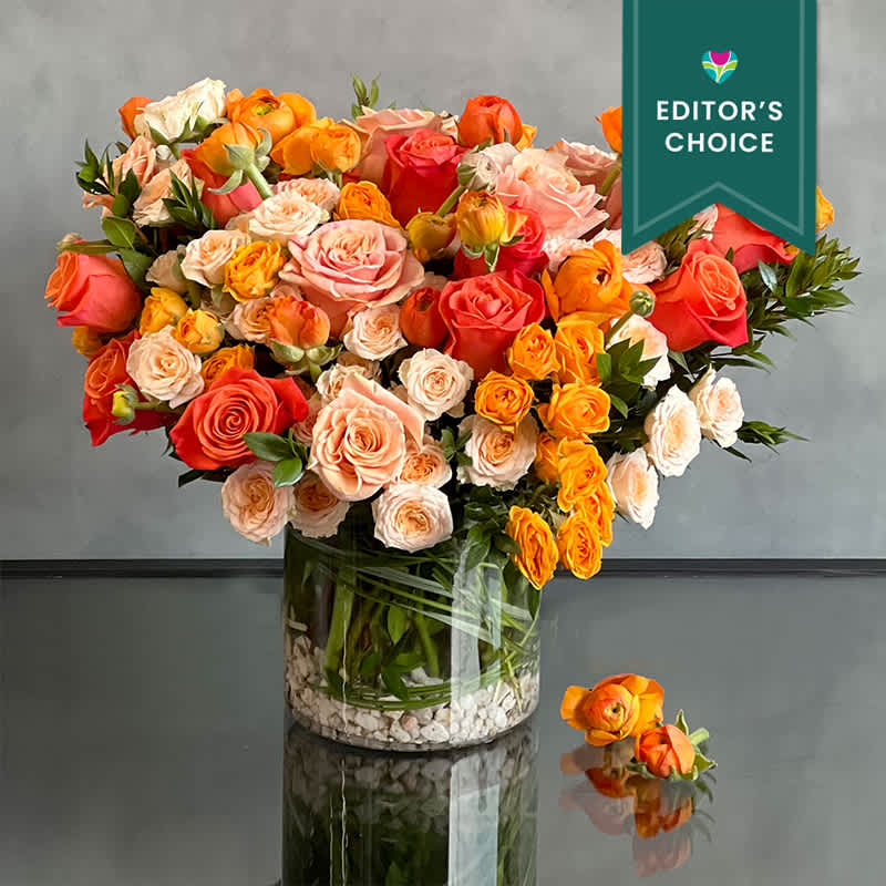 Peachy Sunset Peachy Sunset - Upscale and uptown, this fantastic arrangement features Orange roses, peach spray rose, Locally Grown Flowers and , pops of Green in a clear glass vase. This eclectic mix of florals is sure to delight!