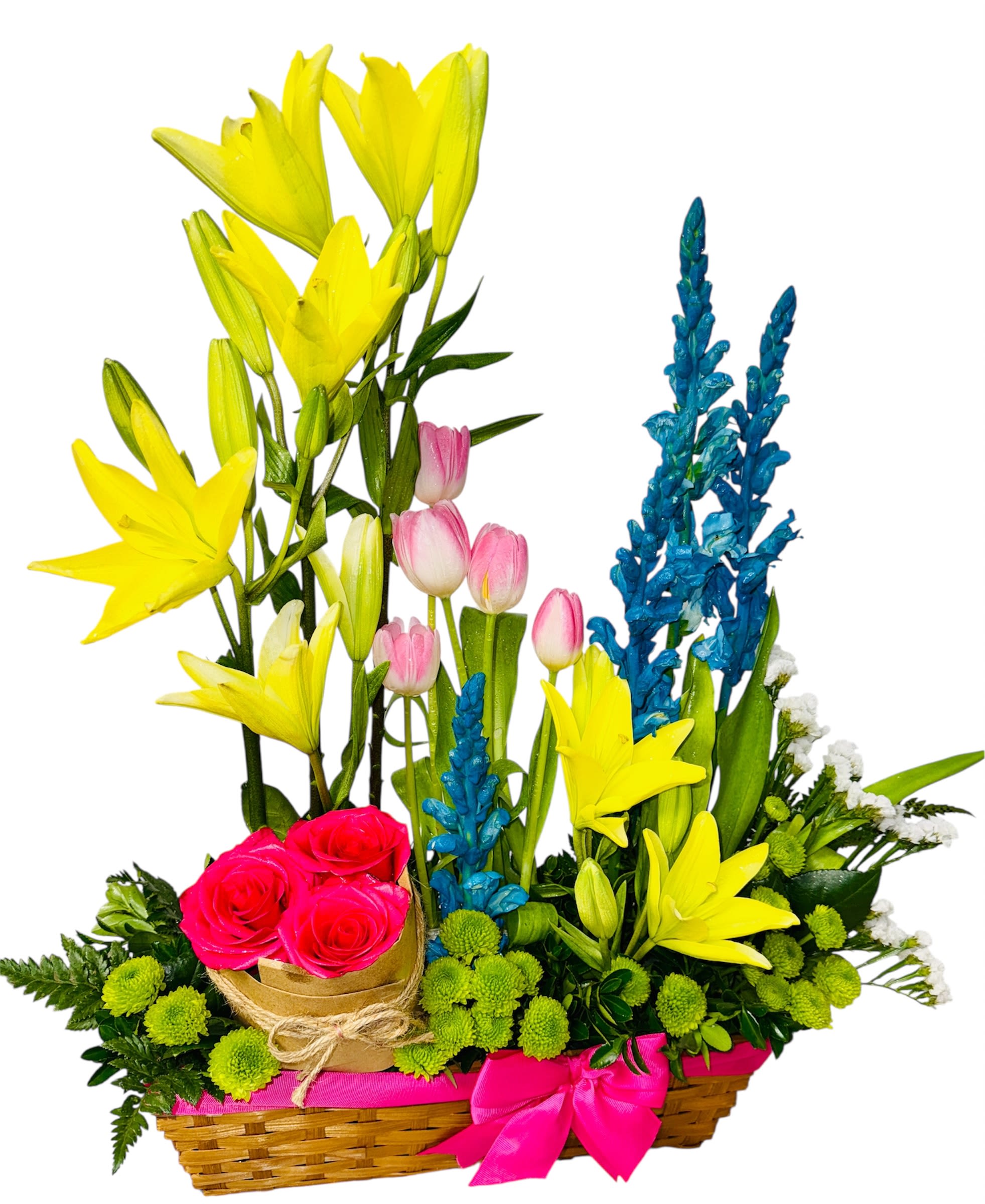 Spring Mosaic - This delightful basket bursts with joyful color and artful composition, blending bright yellow lilies, graceful pink tulips, electric blue delphiniums, and rich red roses. Green button poms dot the arrangement like playful accents, while lush foliage adds fullness and movement. The pink ribbon bow on the wicker basket brings a feminine, celebratory touch, making it feel like a curated masterpiece of springtime emotion—perfect for birthdays, housewarmings, or radiant “just because” moments.