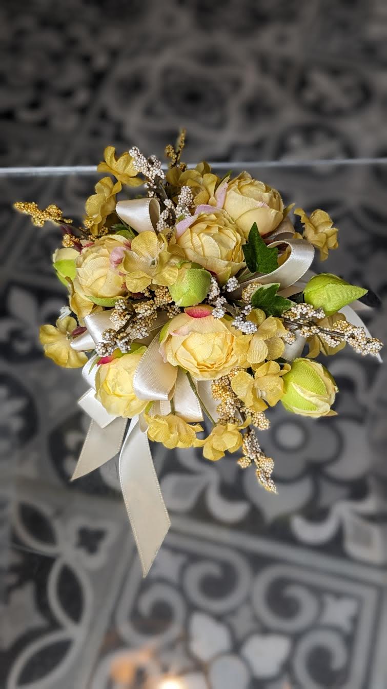 Hello Sunshine Silk Wrist Corsage Hello Sunshine Silk Wrist Corsage - These are artificial flowers. The flowers and ribbon cannot be changed. It is currently on a white snap band but can be put on a black, silver or gold snap band if needed, if they are available.