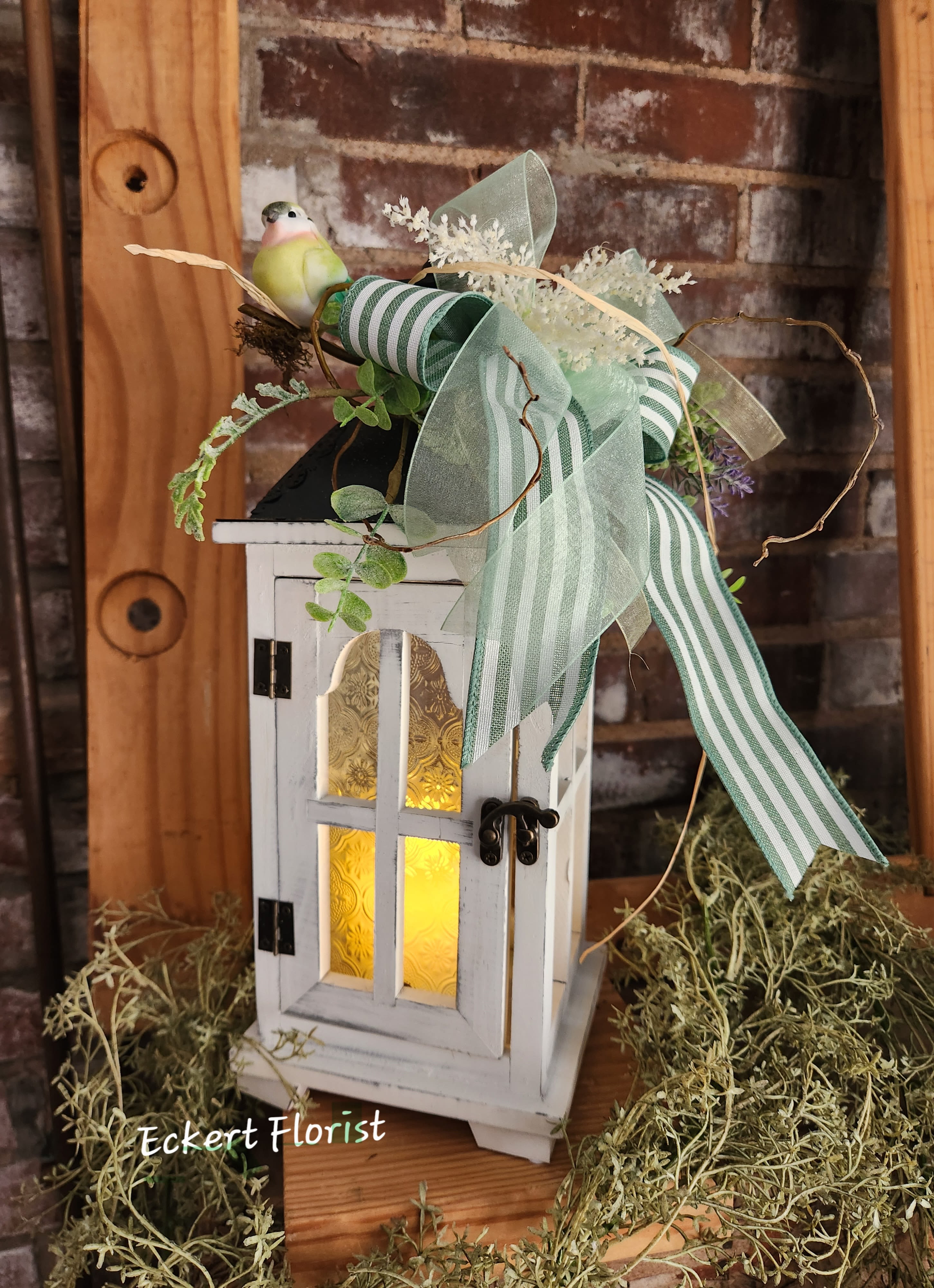 Eckert Florist's Small White Textured Glass Lantern *Our Local Delivery Only Eckert Florist's Small White Textured Glass Lantern *Our Local Delivery Only - This white wooden lantern arrives with textured glass, battery operated candle, floral decor and designer ribbon. Our signature twigs and bird is also included. Lantern measures approx. 16" High x 5.5" Square. Batteries are included. *Our Local Delivery Only