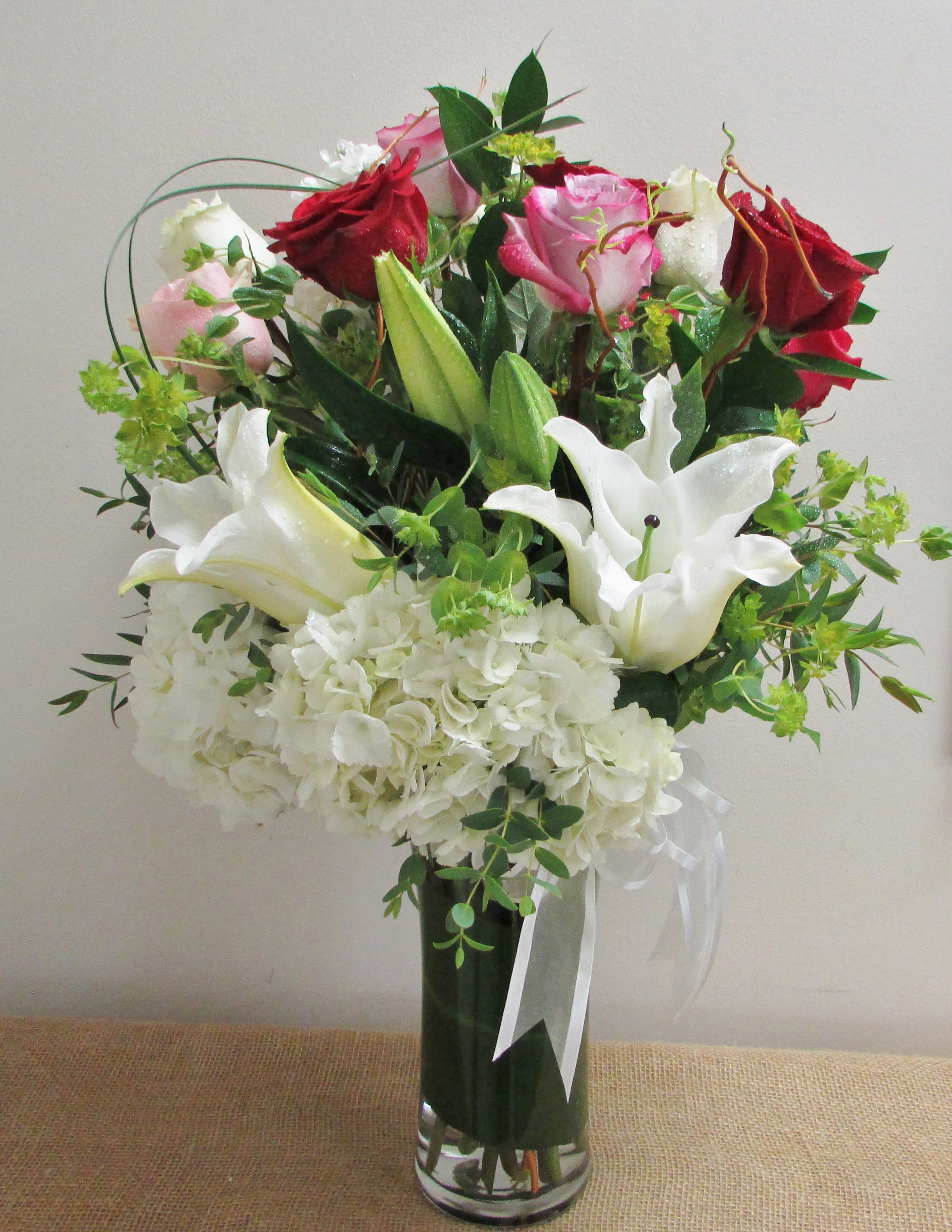 Smile On Your Face Smile On Your Face - A beautiful arrangement of 1 Dozen mixed color roses with hydrangea and lily in a tall vase. The perfect arrangement to bring a smile to your loved one's face