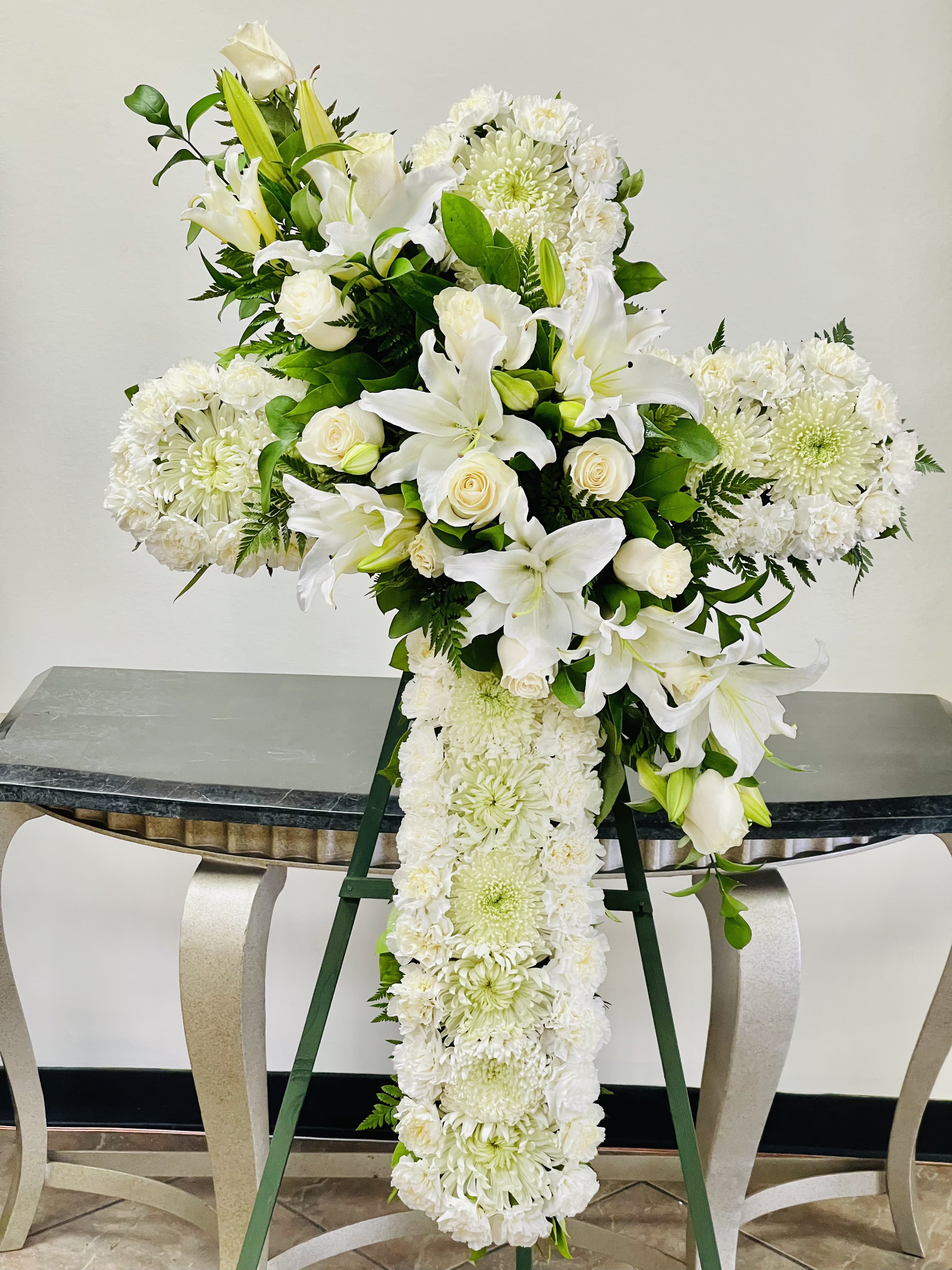 BFS-C14 Funeral Cross - The sympathy cross is a beautiful floral arrangement displayed on an easel stand, measuring 50&quot; in length and 30&quot; in width. It features a thoughtful combination of lilies, roses, mums, and carnations. This arrangement serves as a heartfelt expression of sympathy and support during times of loss, offering comfort and remembrance with its elegant design and choice of flowers.