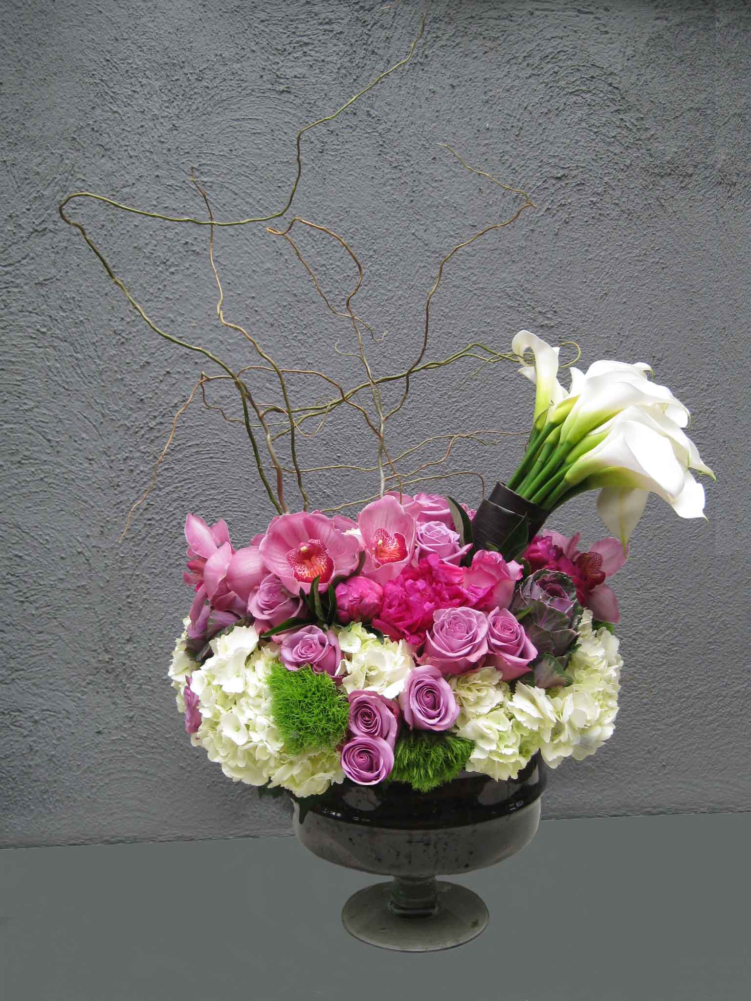 Elegant Celebration - ABR -  A nice assortment of fresh ecuadorian roses, mixed with hydrangeas, dianthus (moss looking flower) accented with a generous mini calla bouquet.Either a glass or metal urn is the upscale container.