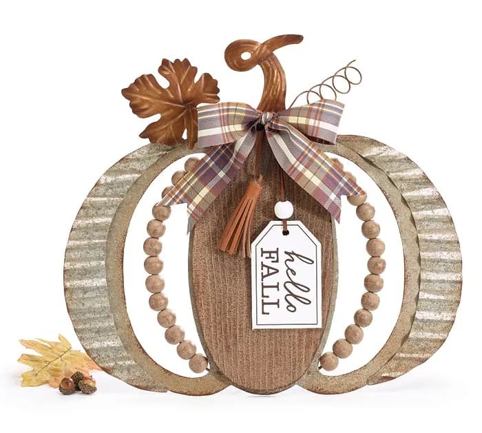 &quot;Hello Fall&quot; Tin Flat Pumpkin  - Primarily corrugated tin in a flat pumpkin shape. Has beaded curves and a brown wooden center that has a white tag hanging down with the message, &quot;Hello Fall&quot; Also has a heavy metal twisted stem and a metal leaf on top. There is a fabric, plaid bow tied around the stem.  Easel back or can hang.  13 1/2&quot;H x 14 3/4&quot;W x 1&quot;D Depth with easel: 3 3/4&quot;D 