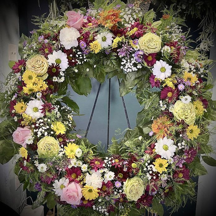 Garden Funeral Wreath - A delicate ring of garden blooms—roses, daisies, and seasonal florals in warm, natural tones—“Garden Funeral Wreath” evokes the peace of a life lived close to nature. This wreath offers a gentle, grounding tribute: a floral embrace, a circle of continuity, a celebration of beauty that never truly fades.  For honoring those who brought light, warmth, and quiet joy into the world.