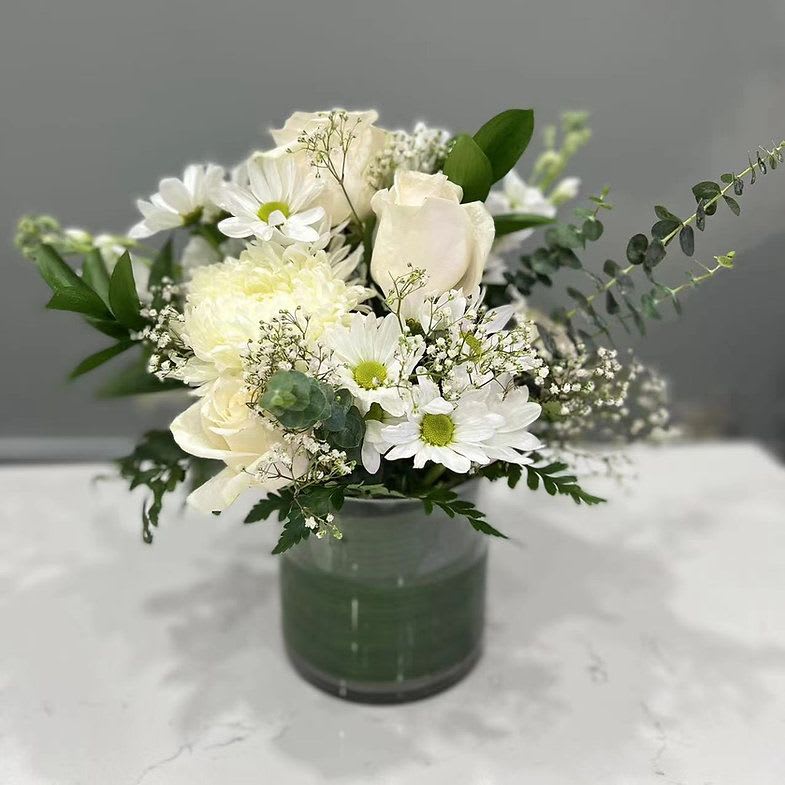 Pretty in White - A soft arrangement in white and green, “Pretty in White” evokes the calm of a quiet morning: sunlight on linen, a freshly washed teacup, the hush of home. Inspired by the balance of old-world still life and contemporary minimalism, this petite arrangement brings a breath of calm to any table or windowsill.  Perfect for housewarmings, thank-yous, or simply making a moment feel held.  