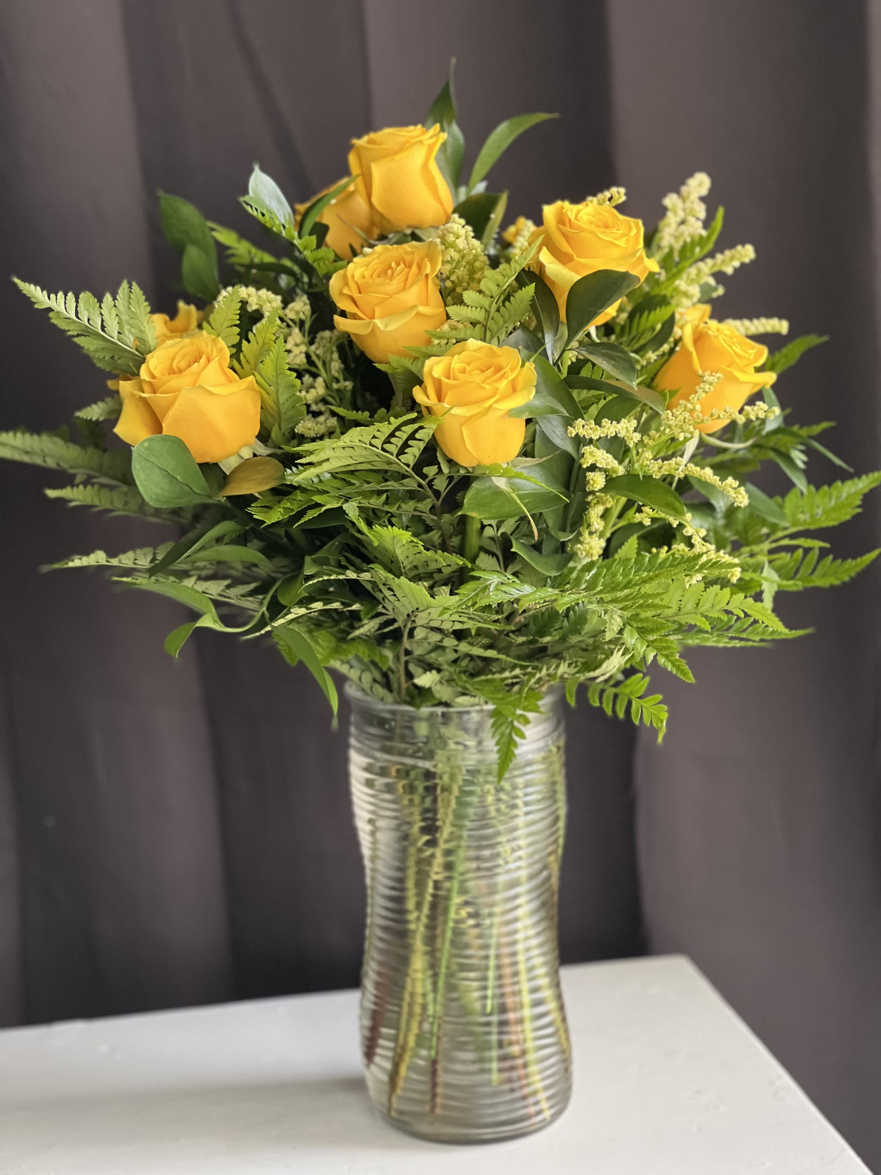 Traditional Dozen in Yellow - Show someone how much you care with a dozen yellow roses! Premium long stemmed roses are designed beautifully with lush greens. Upgrade to 24 or 36 roses to really spoil them!  Vase height is 10.5 inches.