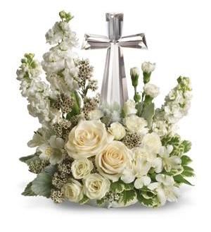 CROSS OF FAITH  NEW-S82 - The CROSS OF FAITH arrangement is a traditional expression  of all white , roses, lilies, and other premium white flowers  enhanced with a quality Crystal Cross rising out of the center of the flowers.. This quality Crystal Cross will be a treasured keepsake by the family and will be a reminder of your love and friendship during the time of the loss of  there loved one. 