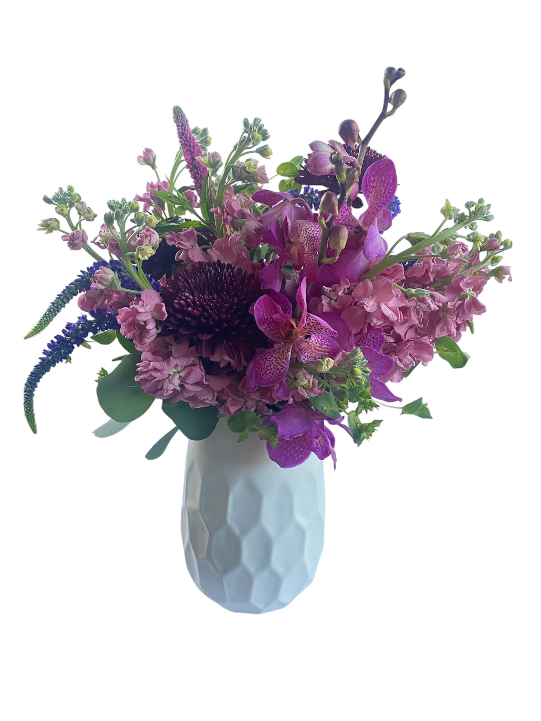 Lovely Lavender - Lovely lavender blossoms with a variety of veronicas, stock, Mokara orchids, buplerum, burgundy disbud, and touch of silver dollar eucalyptus in a white ceramic vase.
