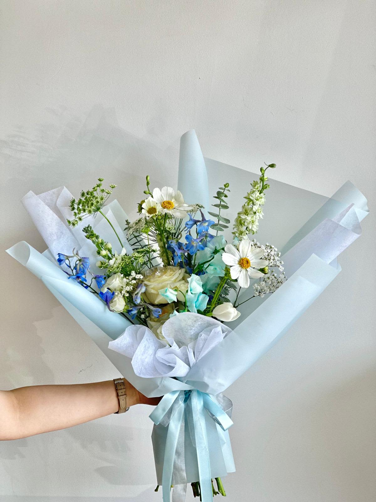 Cinderella  - A bouquet of light blue and white flowers wrapped in light blue paper.   Flower types may vary depending on the season.