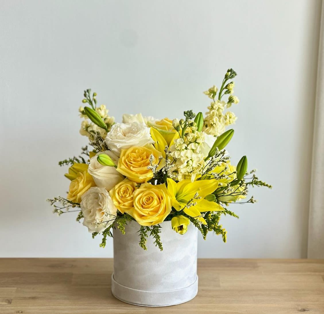 Ivory Sunshine Ivory Sunshine - A medium beige-white velvet box filled with white and yellow flowers. Flower types may vary depending on the season.