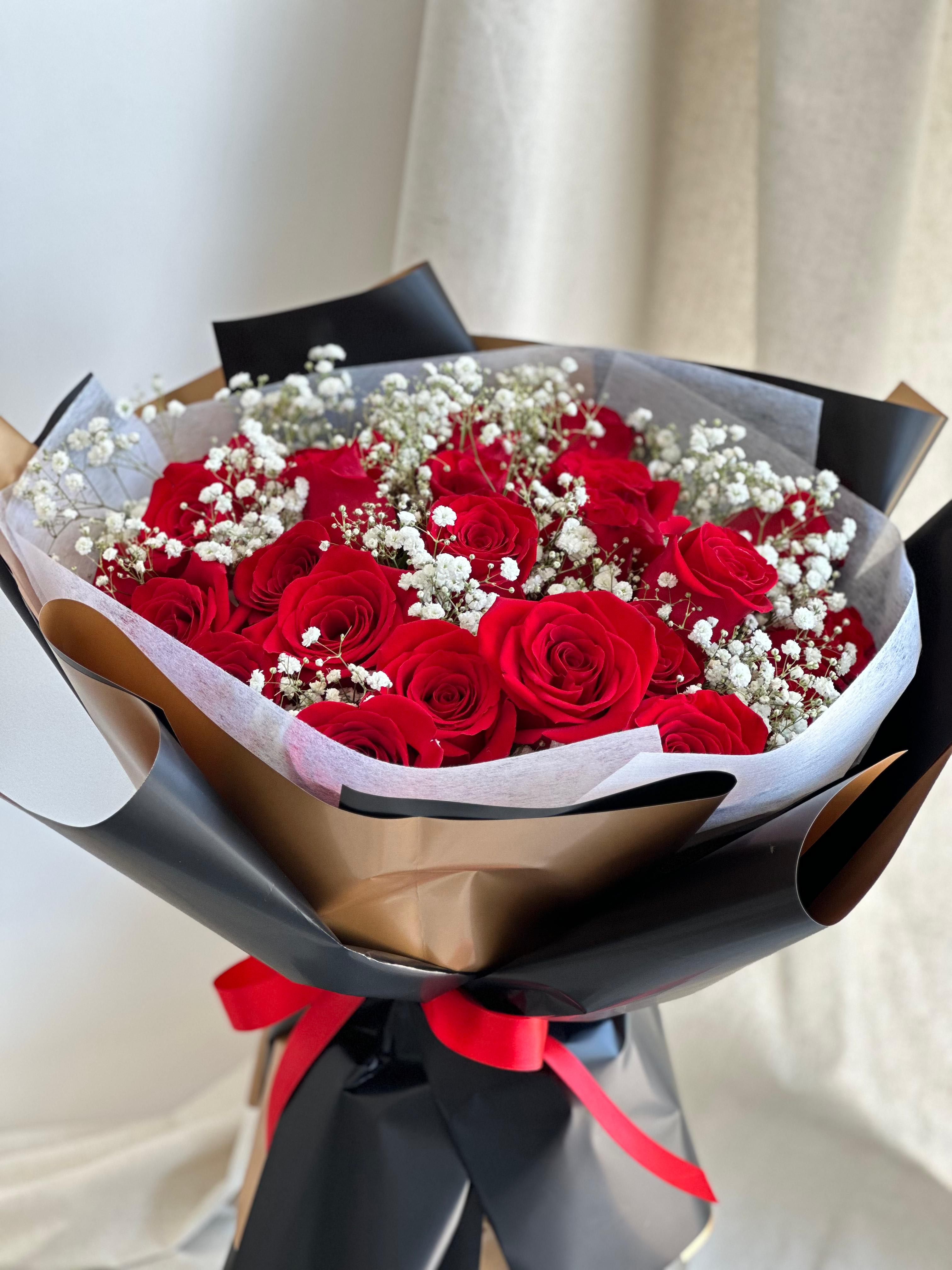 Let Me Love You in Red - A round bouquet of roses and baby's breath, wrapped in black paper.    Flower types may vary depending on the season.