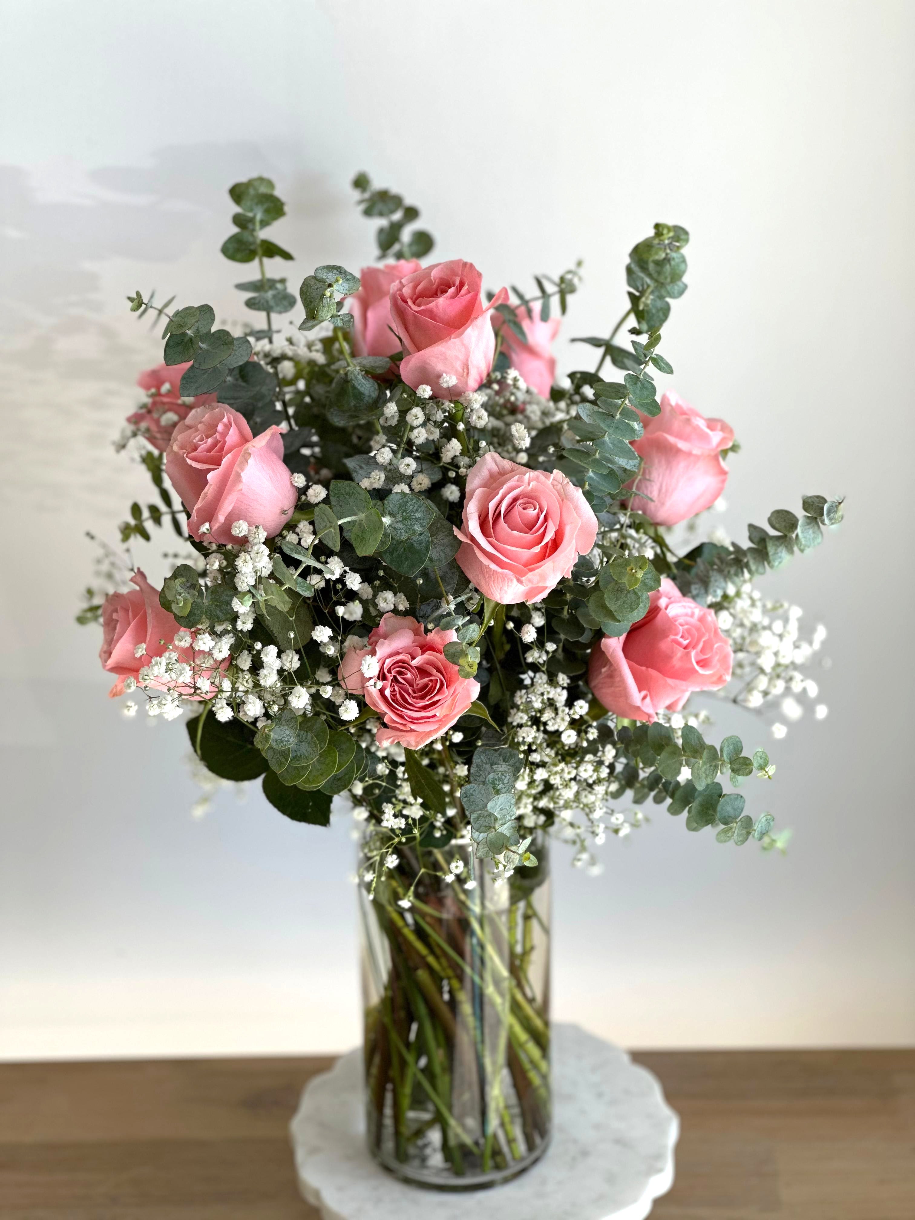 Timeless Romance in Pink Timeless Romance in Pink - A tall cylinder glass vase with roses, eucalyptus, and baby's breath. Flower types may vary depending on the season.