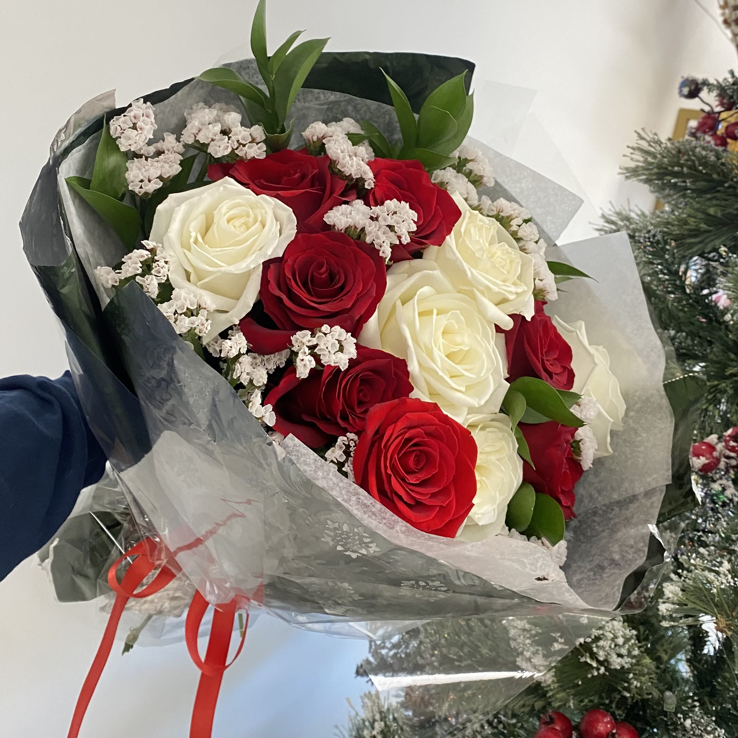 True Romantic True Romantic - A round bouquet of red and white roses with greenery, wrapped in foil and clear paper. Flower types may vary depending on the season.