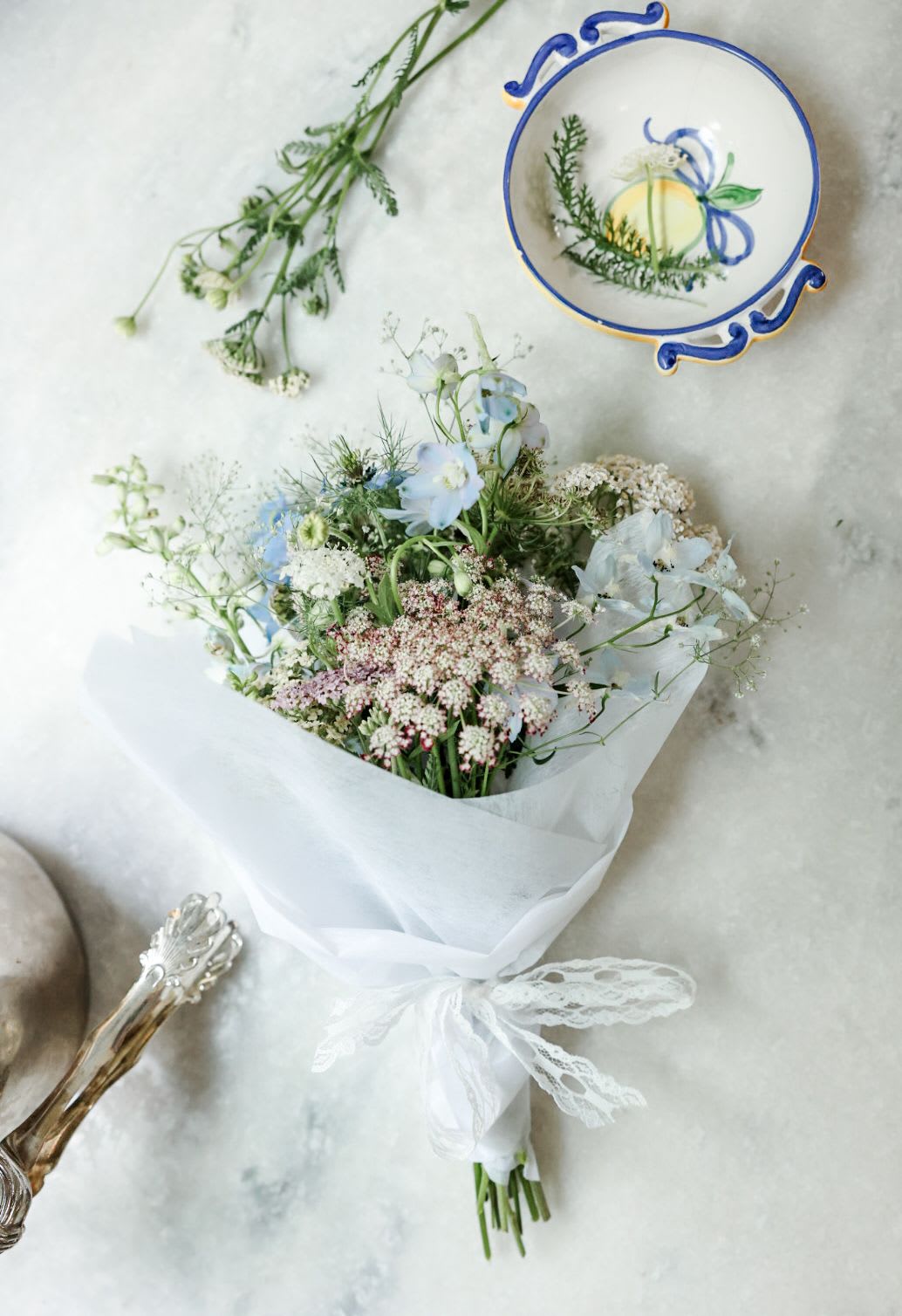 Airy Pastels  - A selection of soft florals from the garden. This arrangement is full of delicate flowers and textures in soft blues, lavender, and white. Expect things like: Nigella, Delphinium, Sweet Peas, Dara, and Orlaya. Standard arrangement is a wrapped bouquet. Upgrade for vased arrangements.