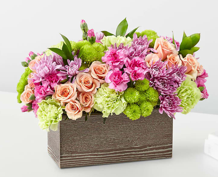 Simple Charm Bouquet - The seasons in bloom with our Simple Charm Bouquet. Gorgeous blooms such as peach spray roses, green button pompon, pink mini carnations and lavender cushion pompons fill a weathered wooden box with freshness. Whether you're saying thank you to a special friend or sharing the most heartfelt get-well message, this arrangement is a breathtaking gift for your loved ones to cherish. (FTD design)