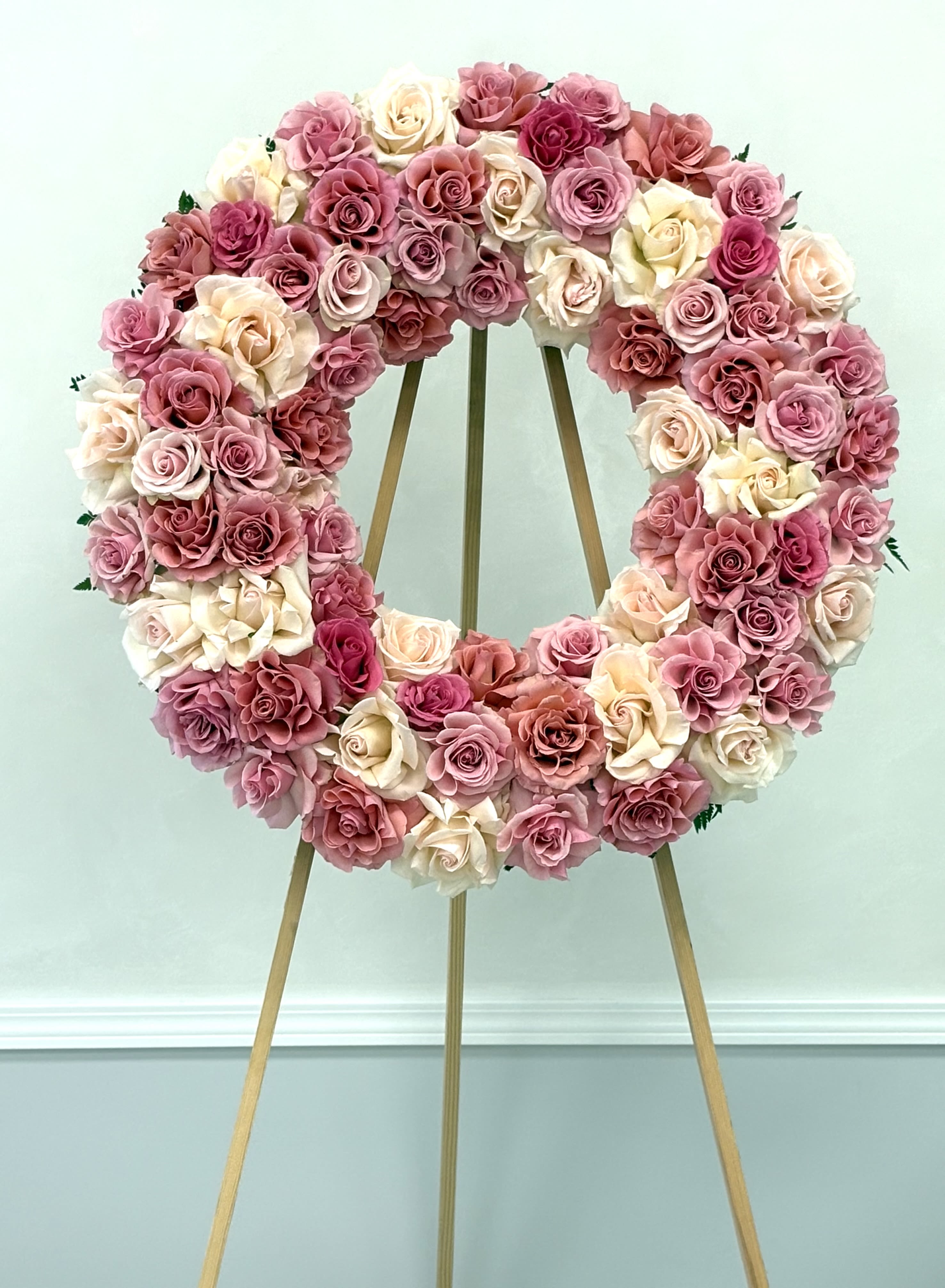 Peaceful Bloom By VLM Flowers - A delicate circle of roses in pastel pinks and creamy whites, symbolizing eternal love and graceful remembrance. This wreath stands as a quiet yet powerful gesture of sympathy and honor.  Perfect For: Expressing condolences with softness and dignity.