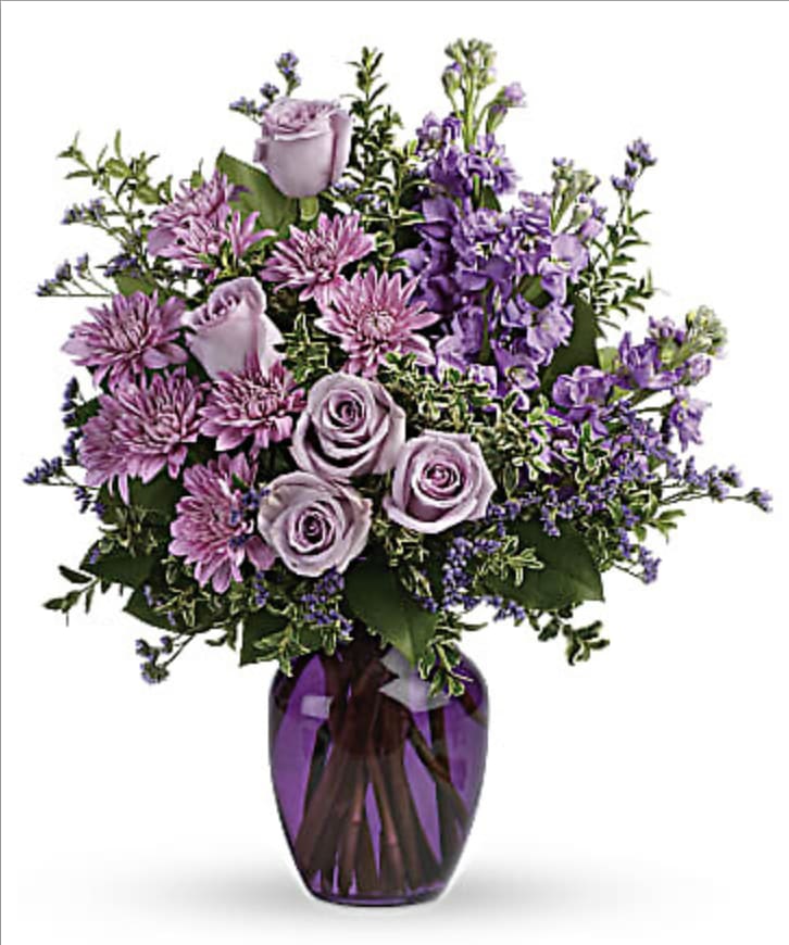 Lavender Haze - Elevate your surroundings with our Lavender Haze Bouquet. Roses, stock, and limonium sit gorgeously atop a generous base of salal, creating a harmonious blend of rich purples and soft greens. Makes the perfect gift for the lover of purple.
