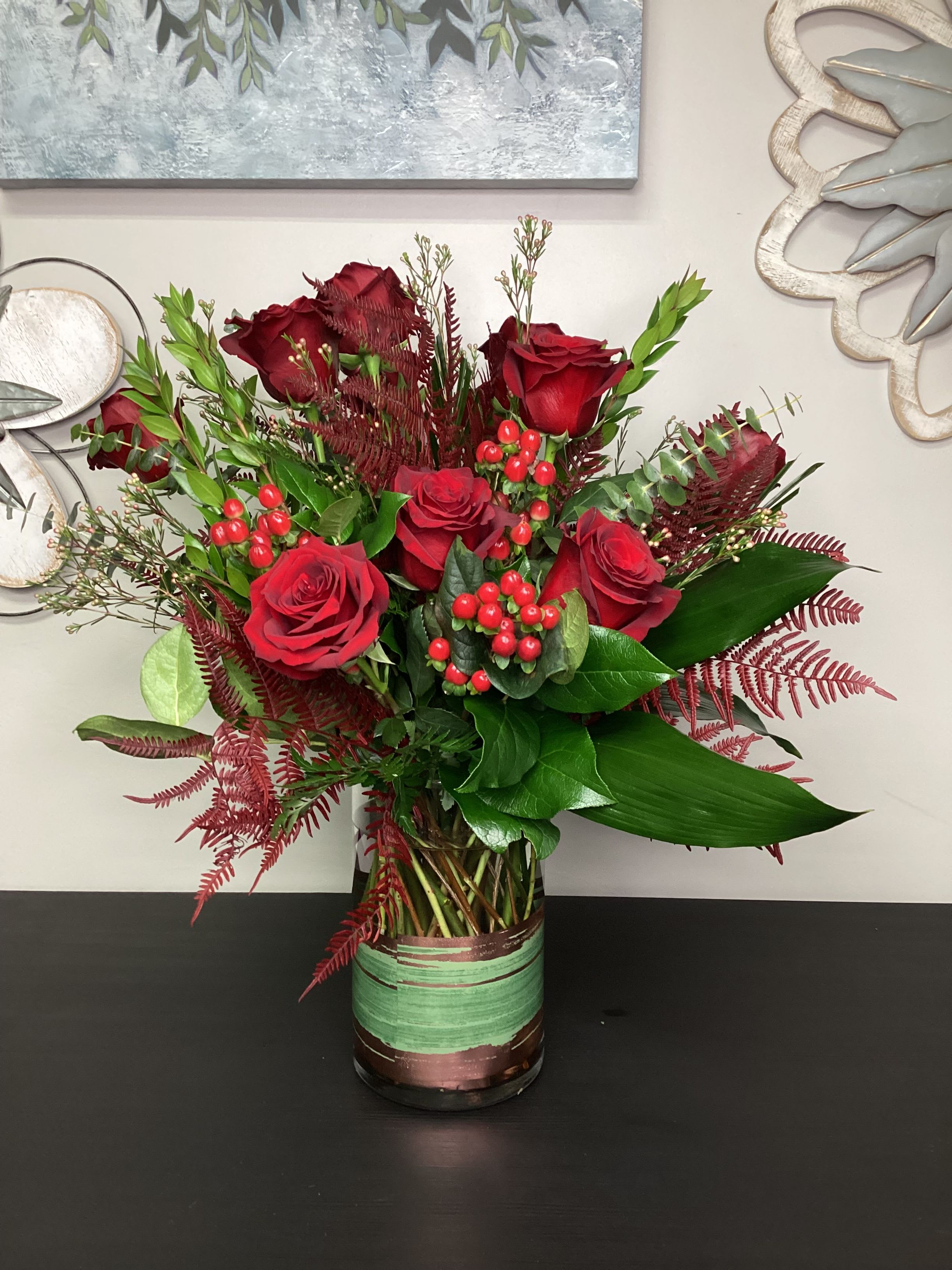 Roses Are Red - Our team puts a lot of love into the stylized designs of our classic dozen rose vase. Giving a swooping motion of emotions into each arrangement. The accents of multiple lush foliage's and movement with perfectly placed branches. 