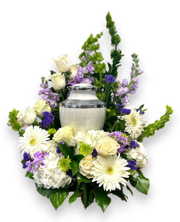 Green, Lavender &amp; White Urn or Photo Tribute - The Green, Lavender &amp; White Urn or Photo Tribute is a beautifully crafted arrangement that combines soft hues and lush textures to create a heartfelt tribute. Featuring delicate Bells of Ireland, fragrant lavender stock, elegant white Alstroemeria, and full white hydrangea, this arrangement is accented with purple Statice, classic white roses, vibrant green button mums, and serene blue ocean mums, all surrounded by rich, mixed greens. Perfect for honoring loved ones, this arrangement exudes tranquility, grace, and a touch of Irish charm, making it a meaningful centerpiece for remembrance or celebration of life.  (Urn or Photo not included.)