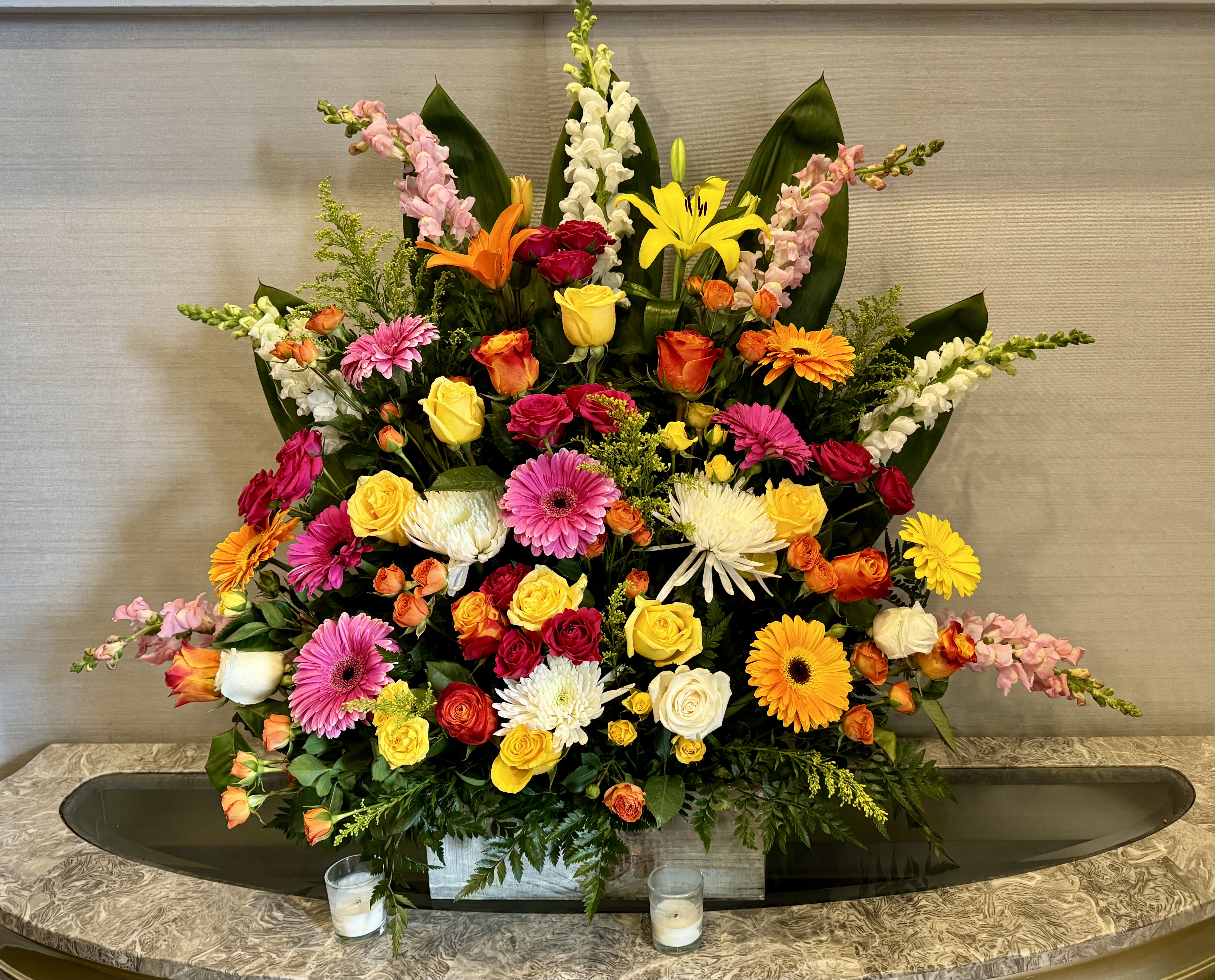 Floral Cascade - A striking, one-sided floral arrangement designed to command attention. Expertly arranged with a luxurious mix of seasonal blooms, this design offers height, dimension, and elegance, making it the perfect choice for entryways, podiums, ceremonies, or any space in need of a bold floral accent.  Color and flower varieties may vary based on season and availability, but each arrangement is created with careful attention to palette, structure, and impact.  *Colors may be substituted. Please let us know in the specials instructions.