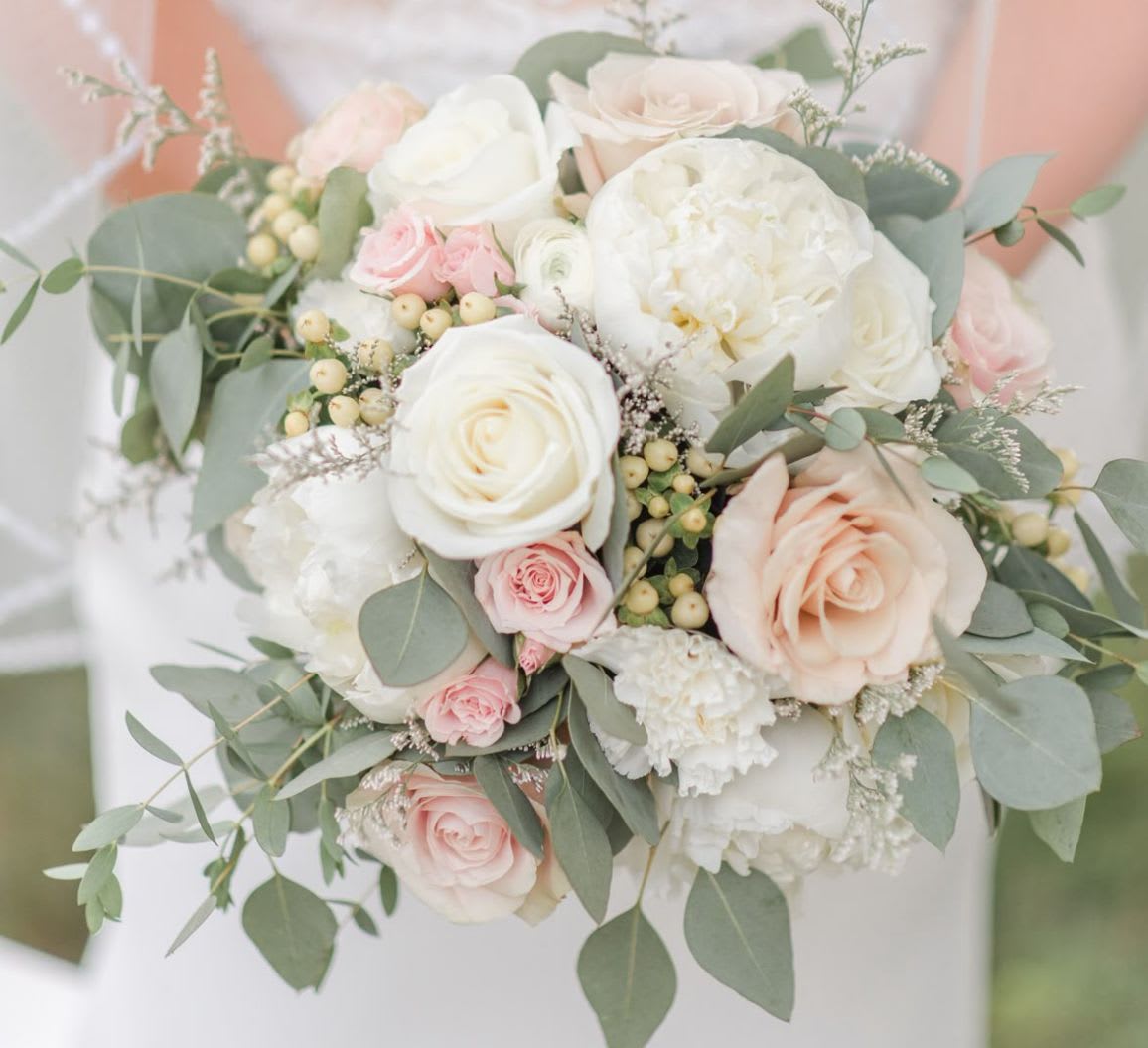 Soft Symphony - A graceful arrangement of creamy white and blush roses, delicate peonies, and soft greenery, Soft Symphony is a romantic floral composition that flows like music. Accented with pale berries and eucalyptus, it’s a perfect balance of elegance, tenderness, and charm — ideal for the classic, refined bride.