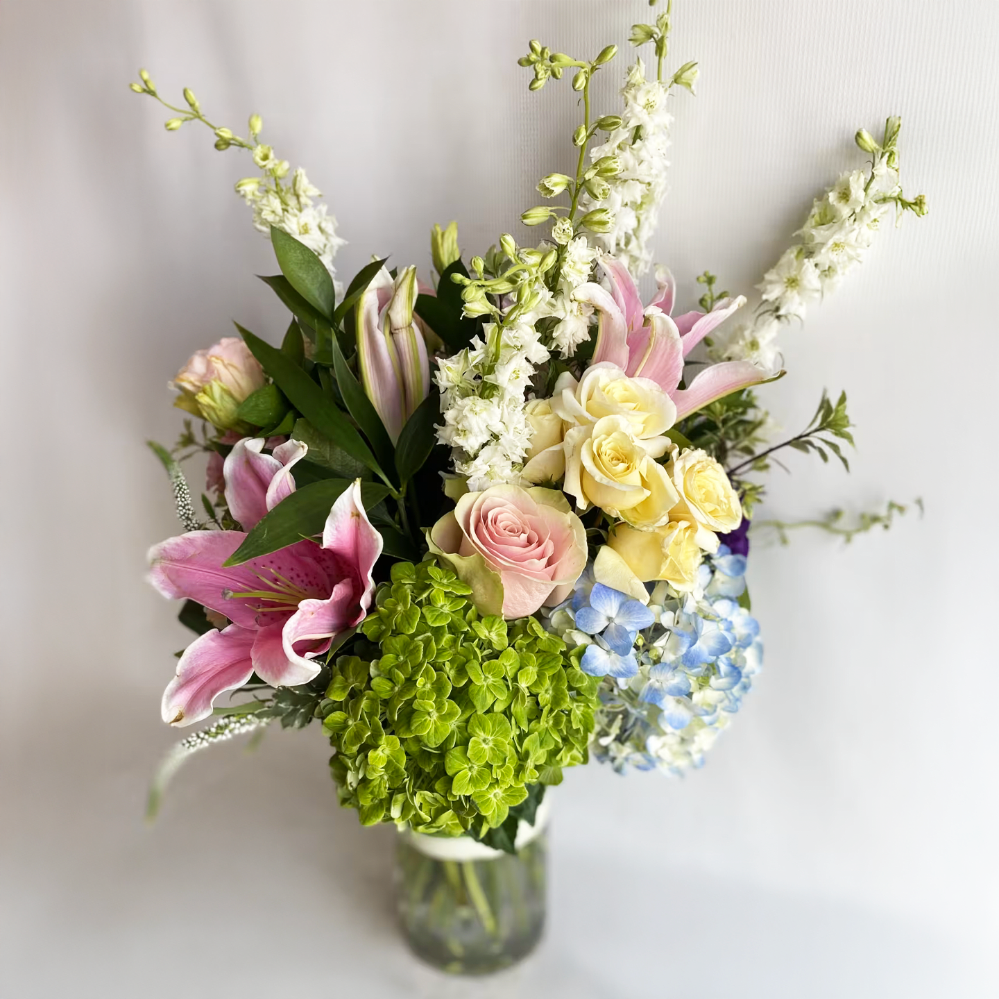 With Love - An arrangement of pink roses, hydrangea, stargazer lilies, and larkspur. 