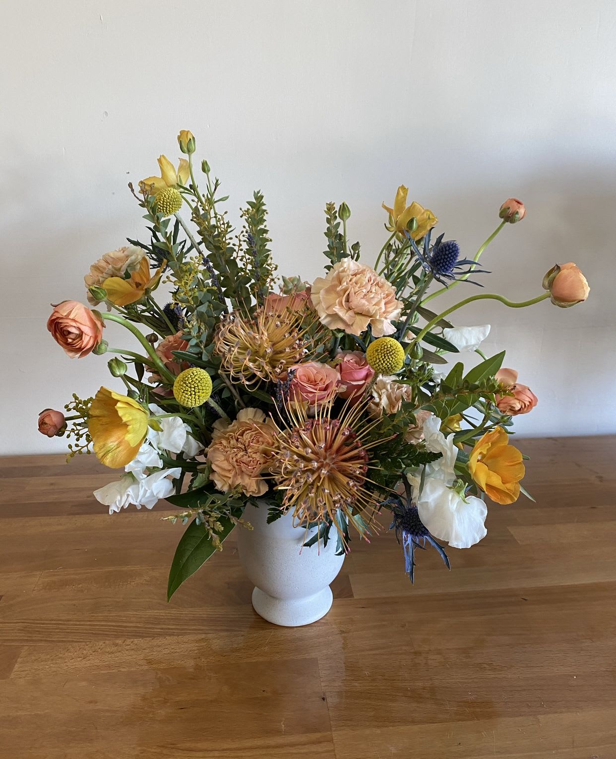Carnival Carnival - "Carnival" is a vibrant burst of color and texture that captures the joyful spirit of celebration and movement. With a playful palette of peaches, yellows, oranges, creamy whites, fresh greens, and unexpected pops of blue thistle, this arrangement feels like a parade of blooms in full swing. Billy balls add a whimsical charm, while layered textures bring energy and depth to the design. Perfect for parties, creative spaces, or simply brightening someone’s day, Carnival is a cheerful escape into color, fun, and floral delight. - Folsom CA florist