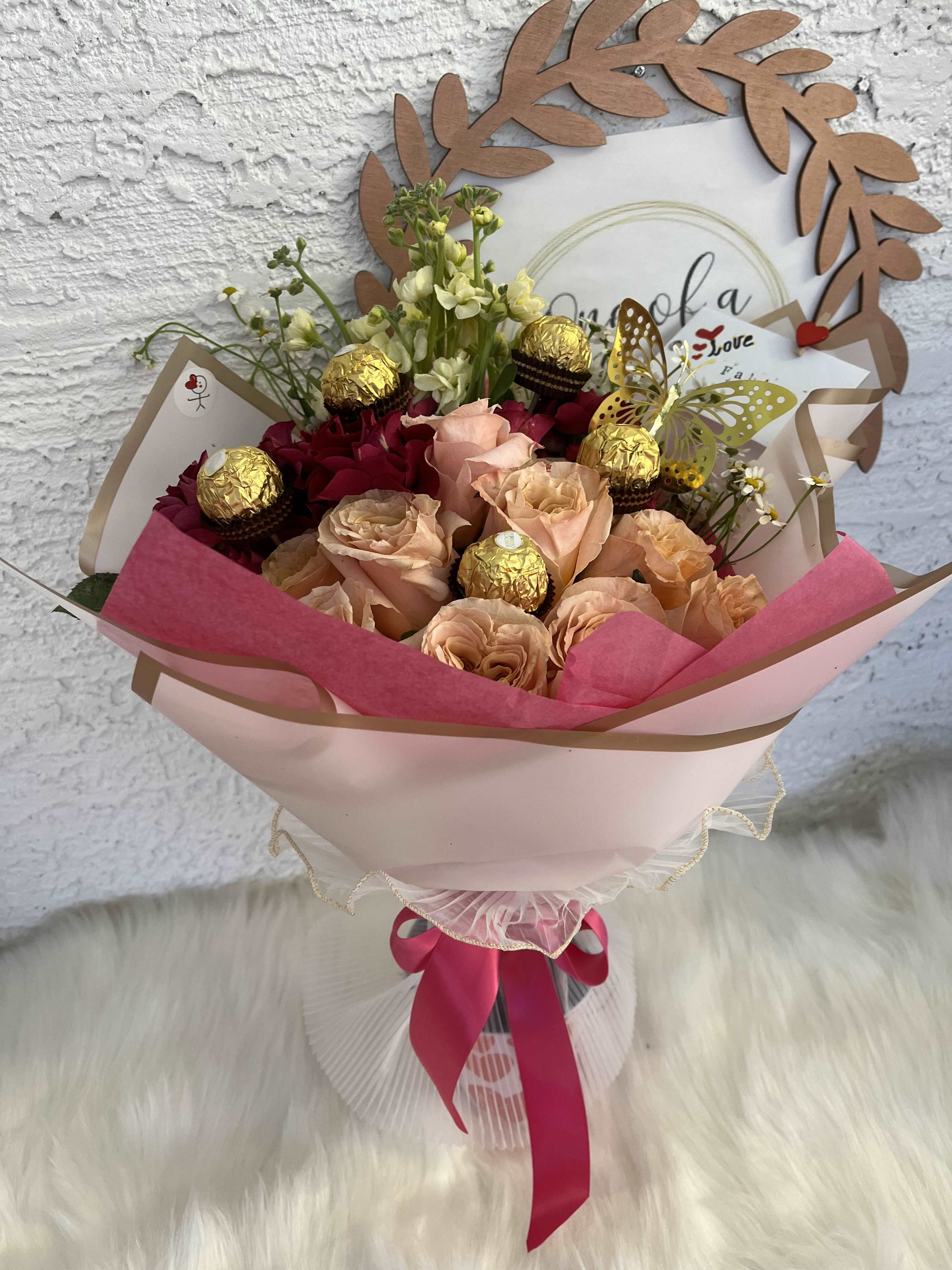 Bouquet Bright dawn - Elegant Rose and Chocolate Bouquet A romantic and luxurious floral arrangement with pink roses, adorned with Ferrero Rocher chocolates and delicate seasonal flowers. Wrapped in soft shades of pink and ivory and finished with a striking bow, this bouquet is perfect for birthdays, anniversaries, or just to make someone feel special.  Flowers and Elements: Pink roses, seasonal flowers, Ferrero Rocher chocolates Style: Romantic, elegant, and a treat Occasion: Birthdays, anniversaries, Valentine's Day, or just because  We customize the color and flowers upon request.