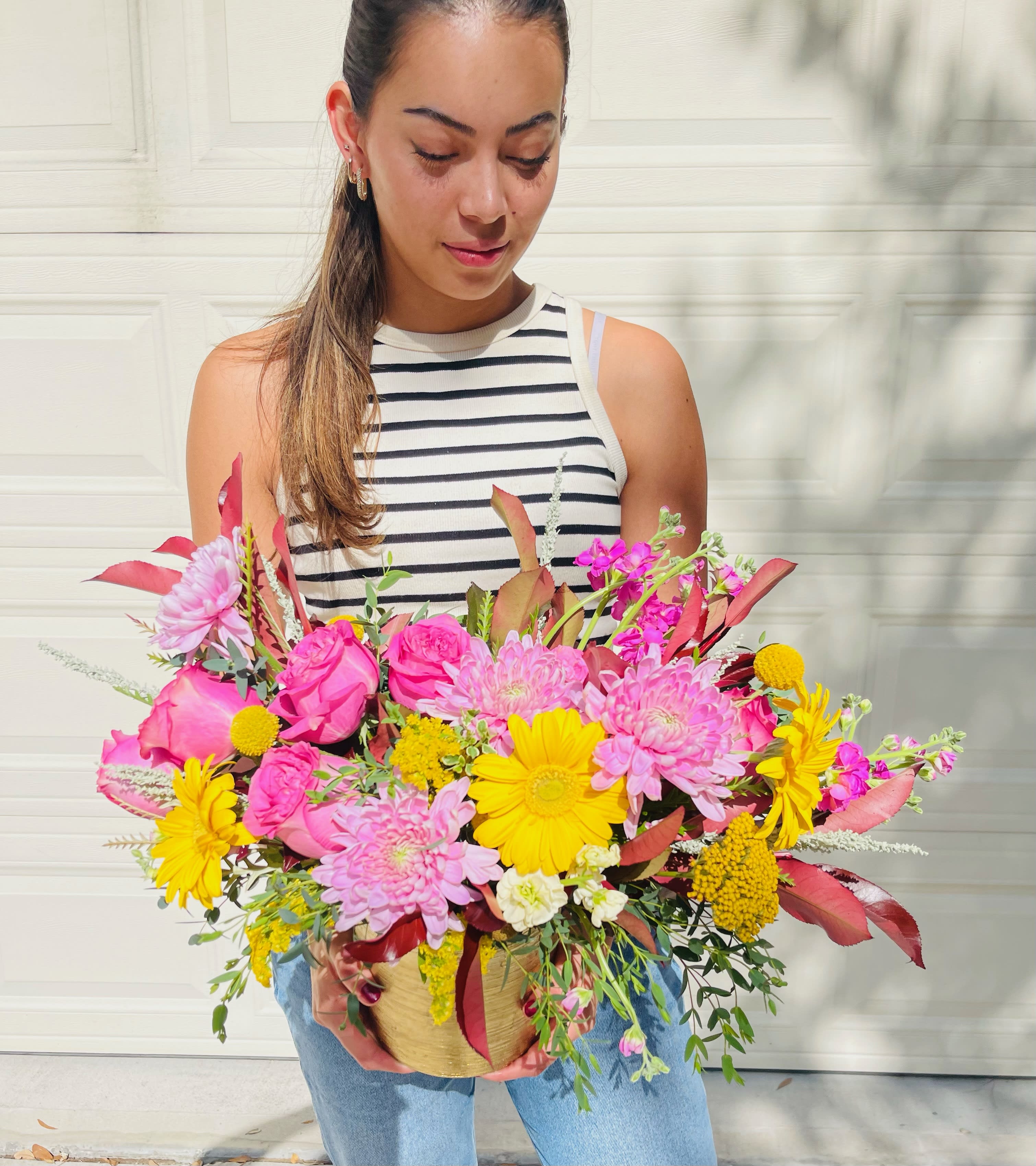 America America - Colorful floral design with gerberas, roses and seasonal foliage.