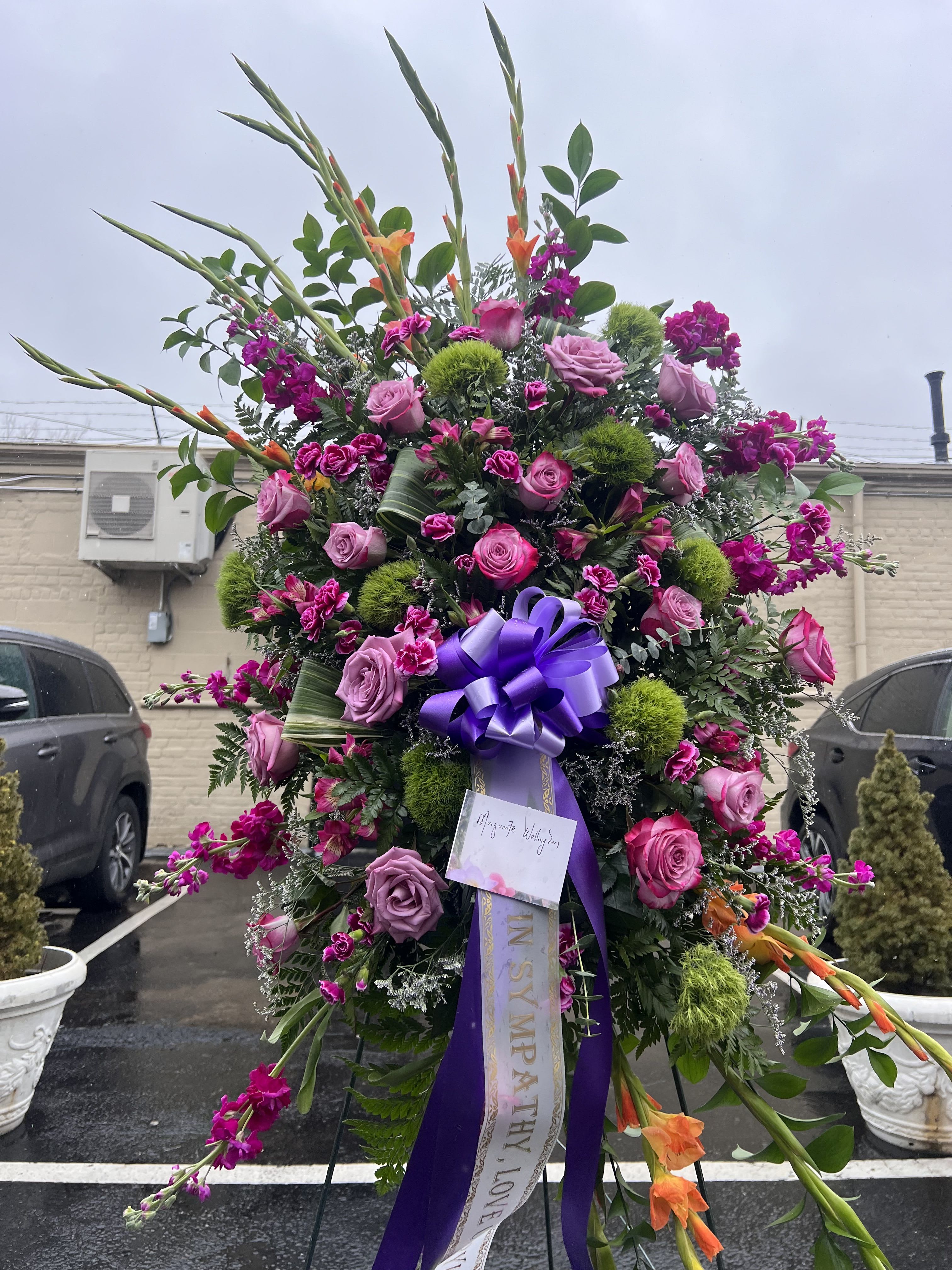Farewell Purple and Green Standing Spray - This spray is a majestic and deeply meaningful funeral arrangement, designed to convey profound respect, enduring remembrance, and heartfelt sympathy. 
