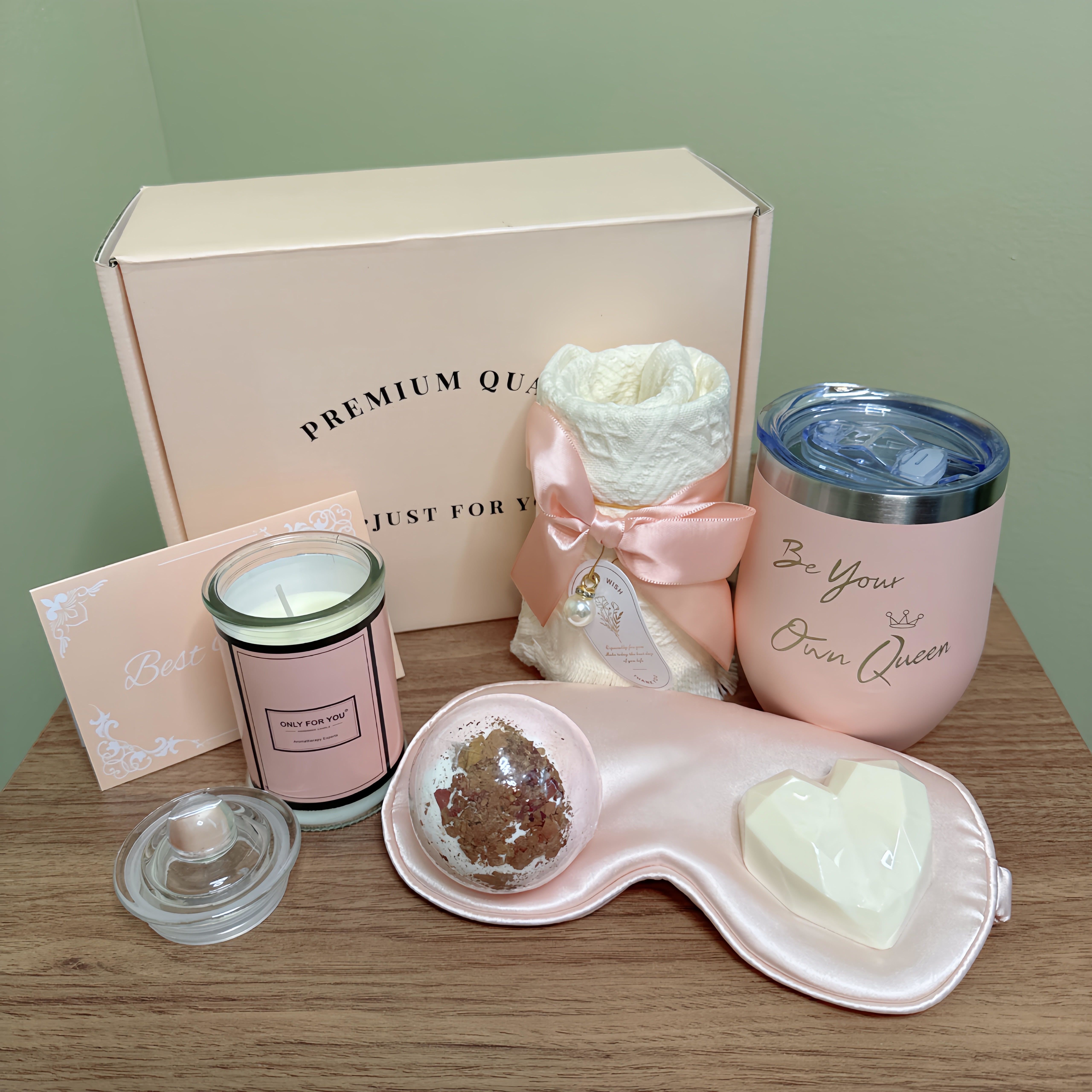 Just For You Gift Set  - This gift set is designed for self-care and relaxation, with items intended to promote a sense of luxury and pampering.   The gift set includes:  - A candle with the label &quot;Only For You&quot; - A pink eye mask with a heart-shaped soap  - A small dish of bath salts - A pink tumbler with the phrase &quot;Be Your Own Queen&quot; - A white loofah sponge in a pink satin bag - A pink card with the words &quot;Best&quot; written on it. 