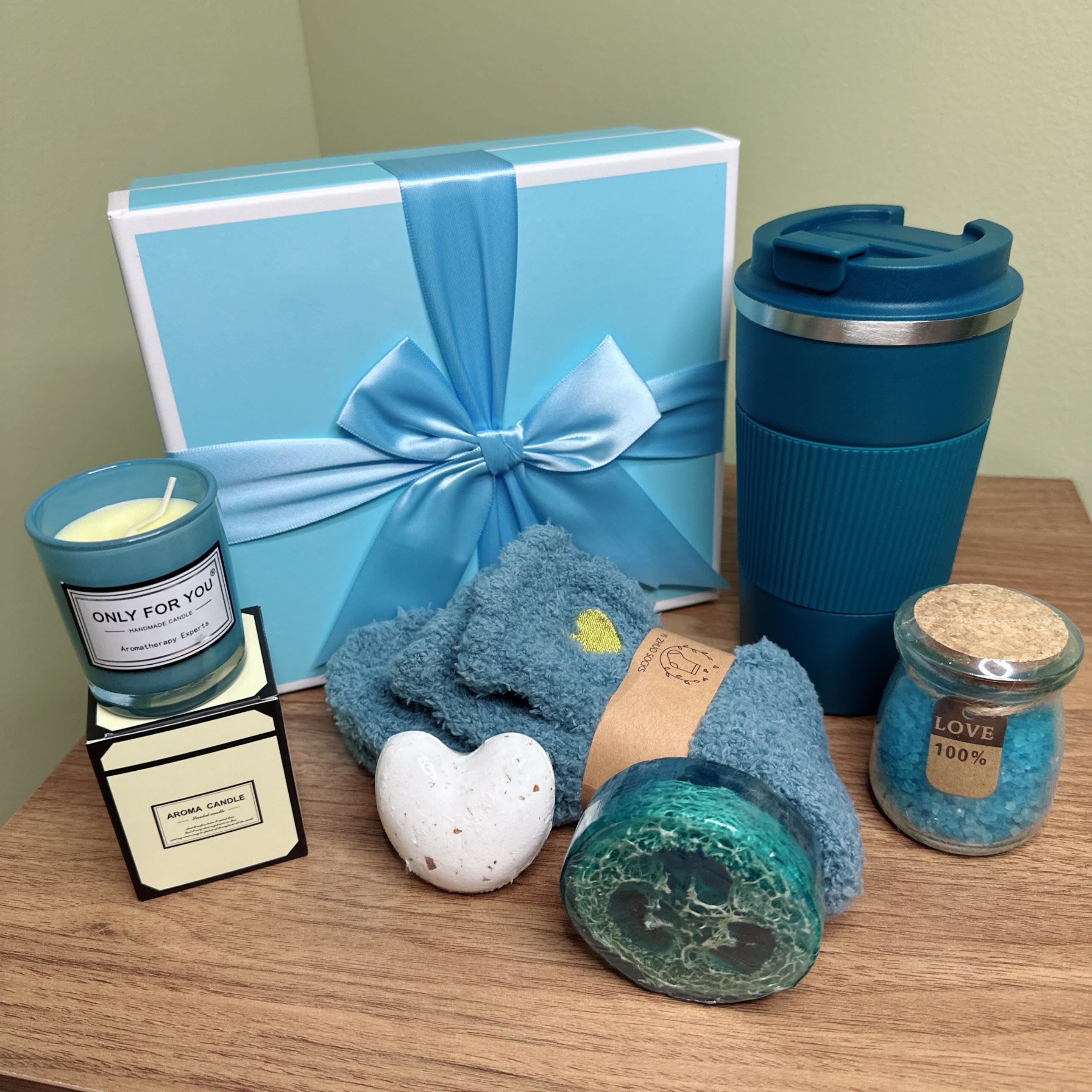  Blue Bliss Gift Set - This thoughtfully curated gift set is designed to promote relaxation and self-care. It includes:  - A soothing candle labeled &quot;Only for You&quot; to create a calming ambiance - A heart-shaped bath bomb for a luxurious bathing experience - A loofah for gentle exfoliation - A reusable mug for hot beverages - A jar of bath salts labeled &quot;Love 100%&quot; to enhance the bathing experience  This gift set is perfect for anyone seeking to unwind and indulge in some me-time. The blue color scheme adds a touch of serenity and tranquility, making it an ideal present for friends, family, or colleagues.