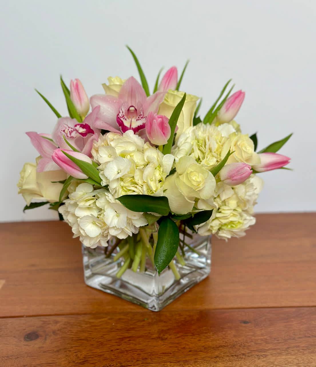 Sweet Success - Like a wave of emotion sweeping through you, is an invitation to listen to your heart and live every moment with passion. Fresh white roses, cymbidium orchids, pink tulips and white hydrangea waft you away into the whirlwind of life.