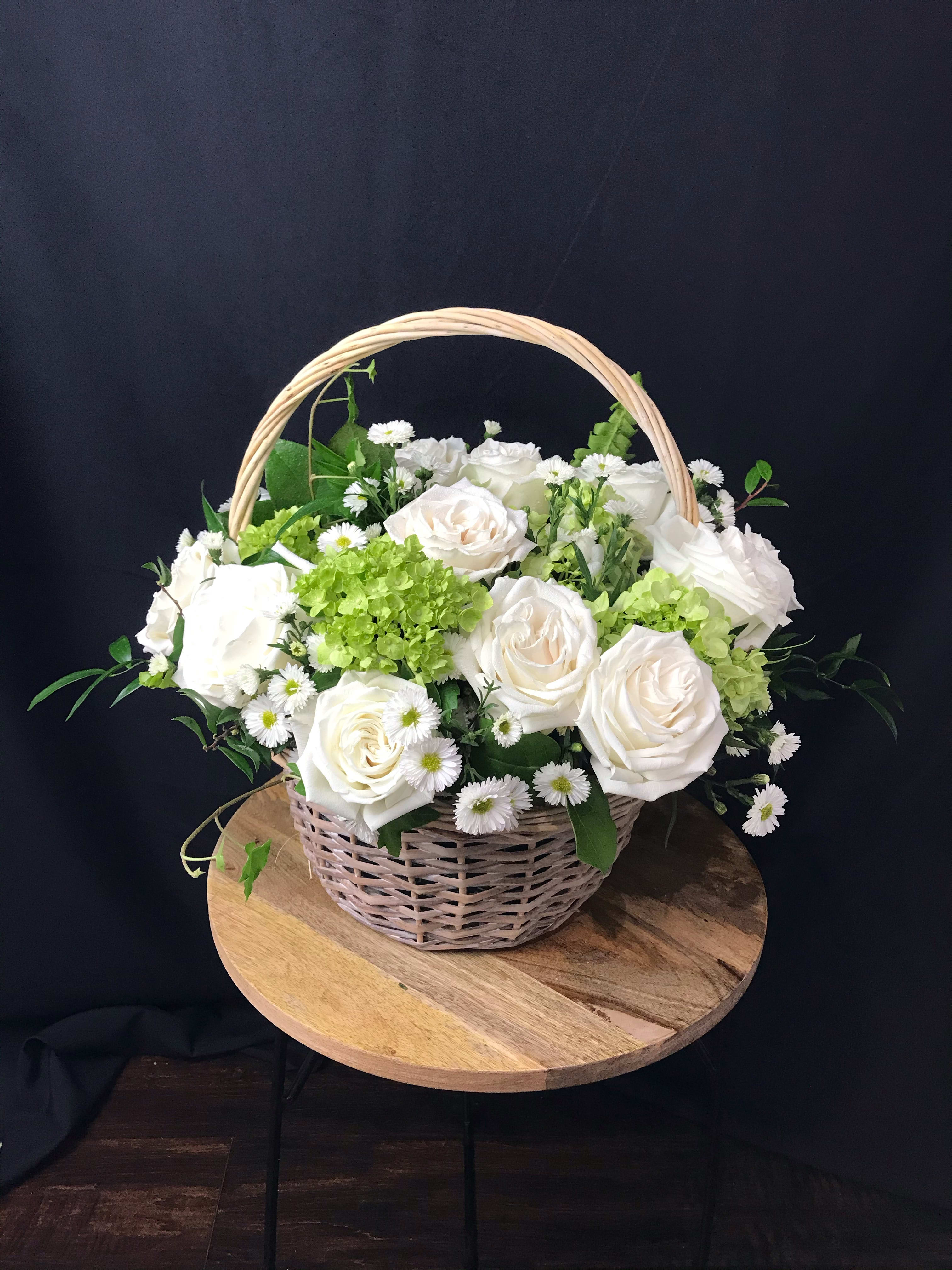 Serene Basket - A lovely basket full of white roses and green hydrangeas nested in mix of ivy and other greens.