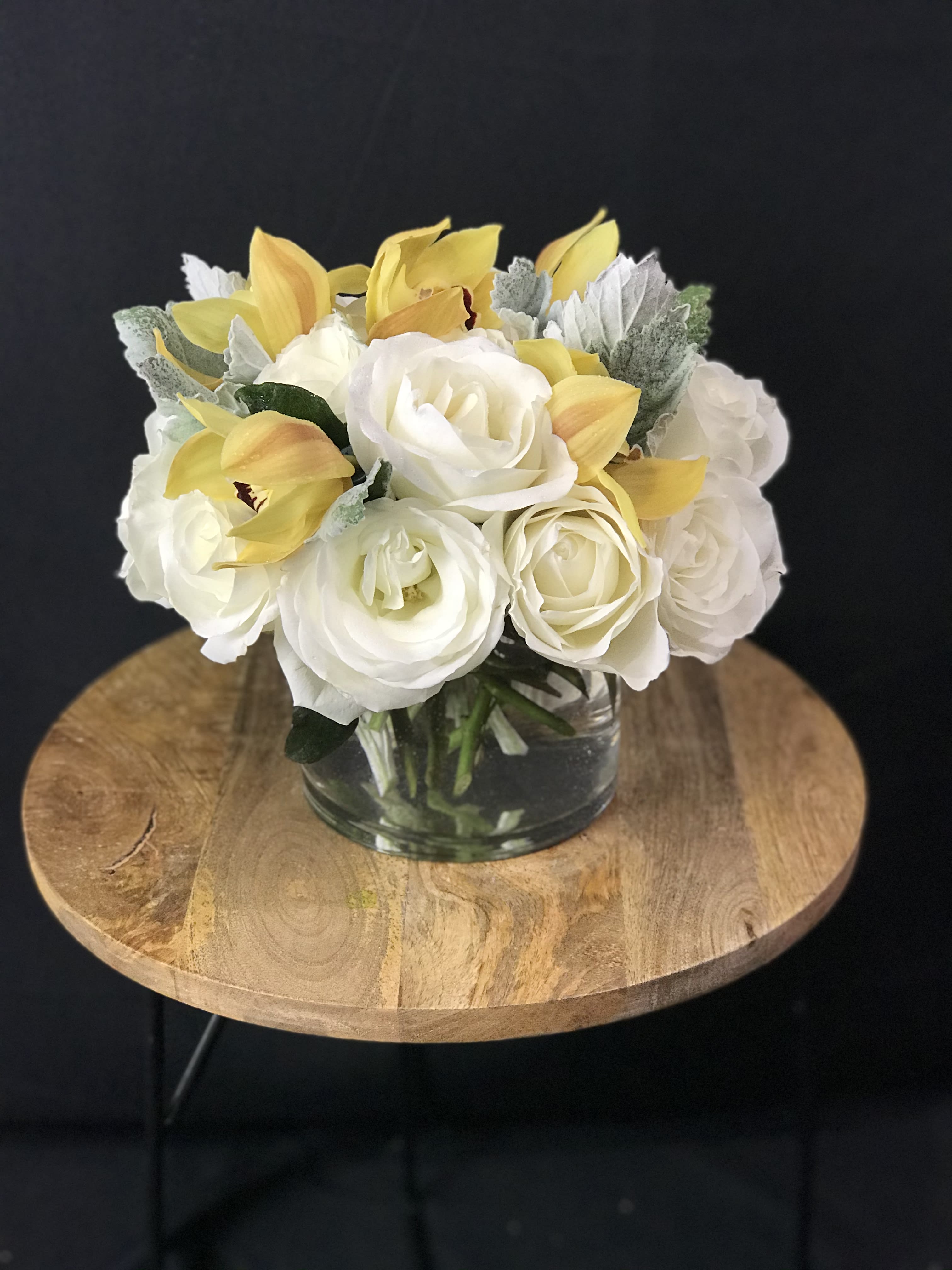 Smooth and Rich - Nested in a bunches of gorgeous white roses are a some lovely yellow orchids with dark green fuzzy dusty millers around their edges. The simplicity and elegance of this piece makes it perfect for absolutely any occasion. 
