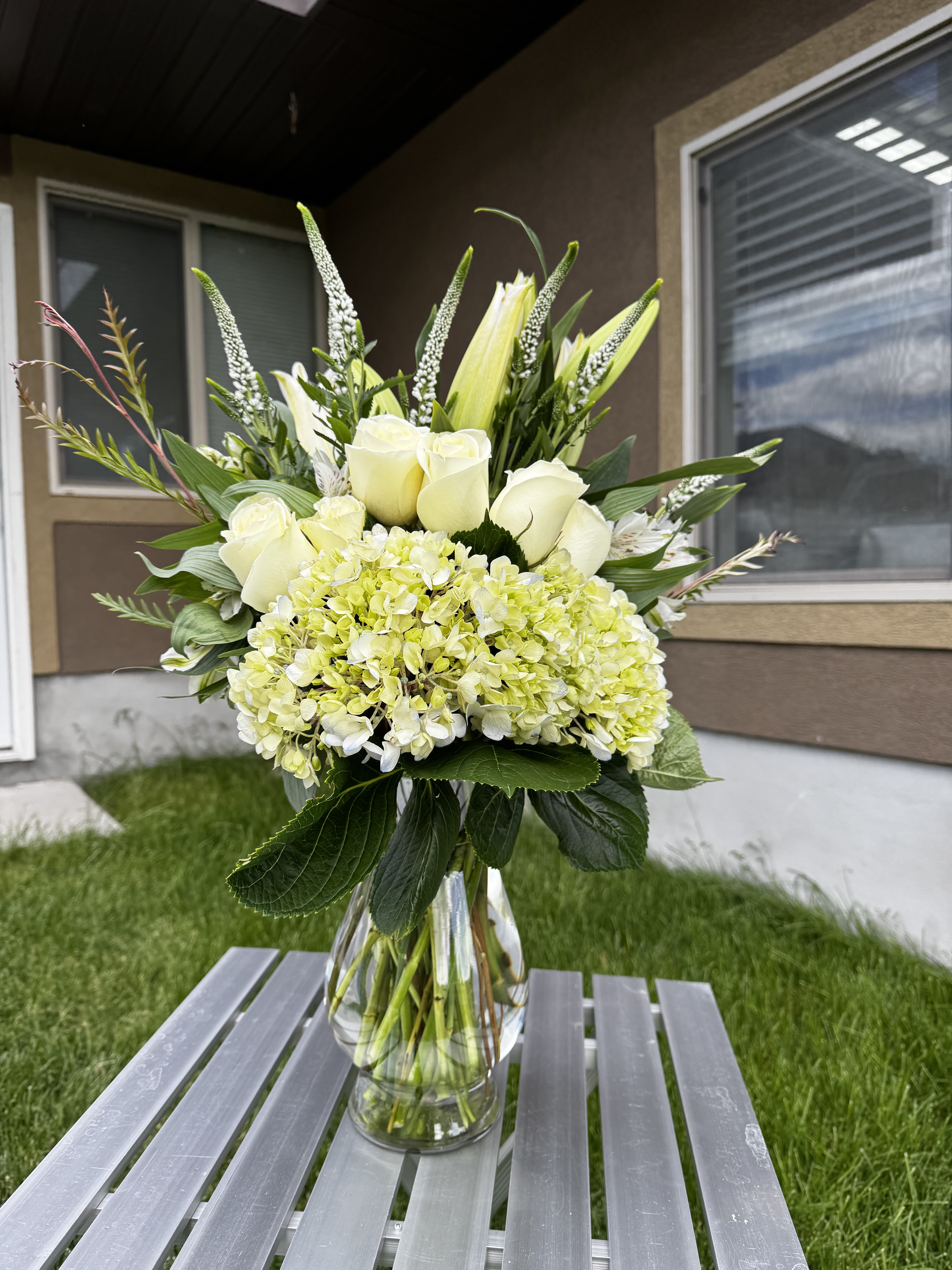 Elegant White Vase - An elegant and timeless gift — our Elegant White Vase features a refined mix of white roses, hydrangeas, Veronica, lilies, and seasonal greenery, beautifully arranged in a clear glass vase. Perfect for sympathy occasions, get well wishes, thank you gifts, or simply to bring peace and beauty into any space. Hand-delivered with care in West Jordan, Utah.#ElegantWhiteVase #SympathyFlowers #WhiteFlowerVase #FuneralFlowers #ElegantFlowersUtah #WhiteRosesArrangement #HydrangeasVase #FreshFlowersWestJordan #WestJordanFlorist #BloomNationFlorist #YelisFlowersAndGifts #SendFlowersWestJordan 