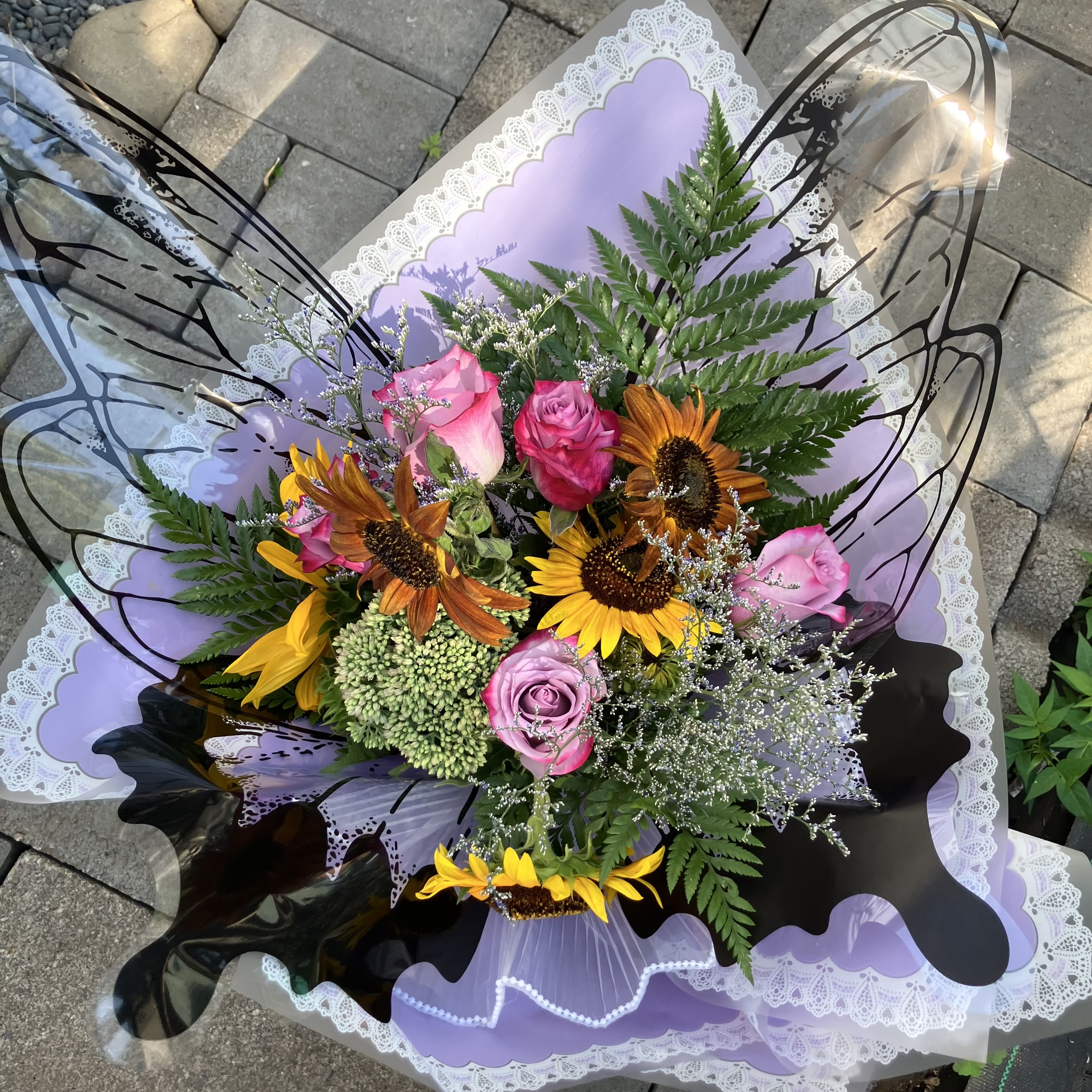Butterfly Bouquet  - Send something uniquely beautiful, a hand tied sunflower and rose bouquet wrapped with butterfly wings and lavender colored wrap 