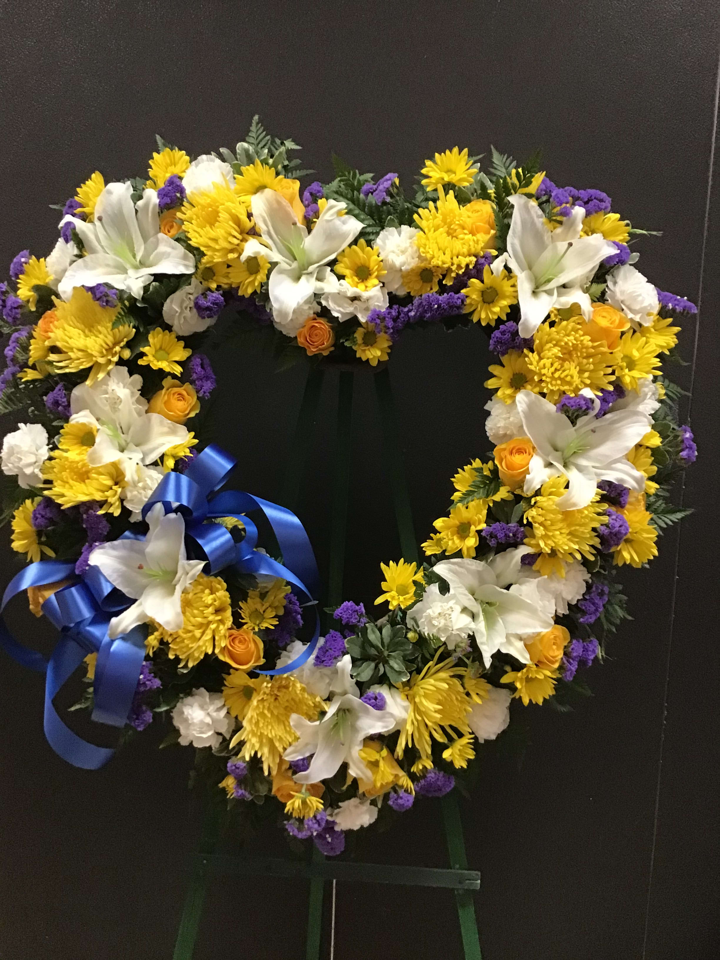 Blue white and yellow open heart (FH22) Blue white and yellow open heart (FH22) - This open heart make with yellow roses and daisies, white lilies and carnations, and finish with blue static and a blue bow.