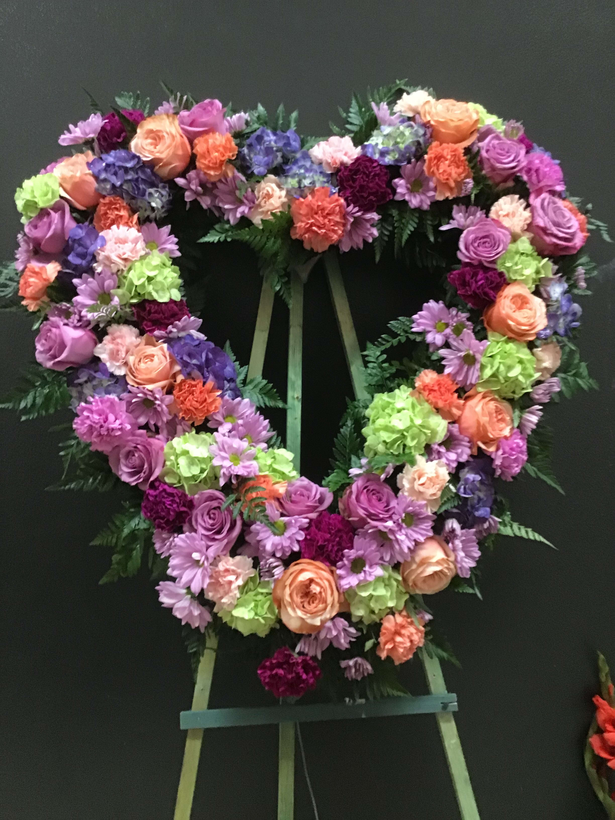Peach and purple open heart (FH23) Peach and purple open heart (FH23) - This open heart made with green hydrangea, purple roses, carnations , daosy. and peach roses. amd orange carnations .