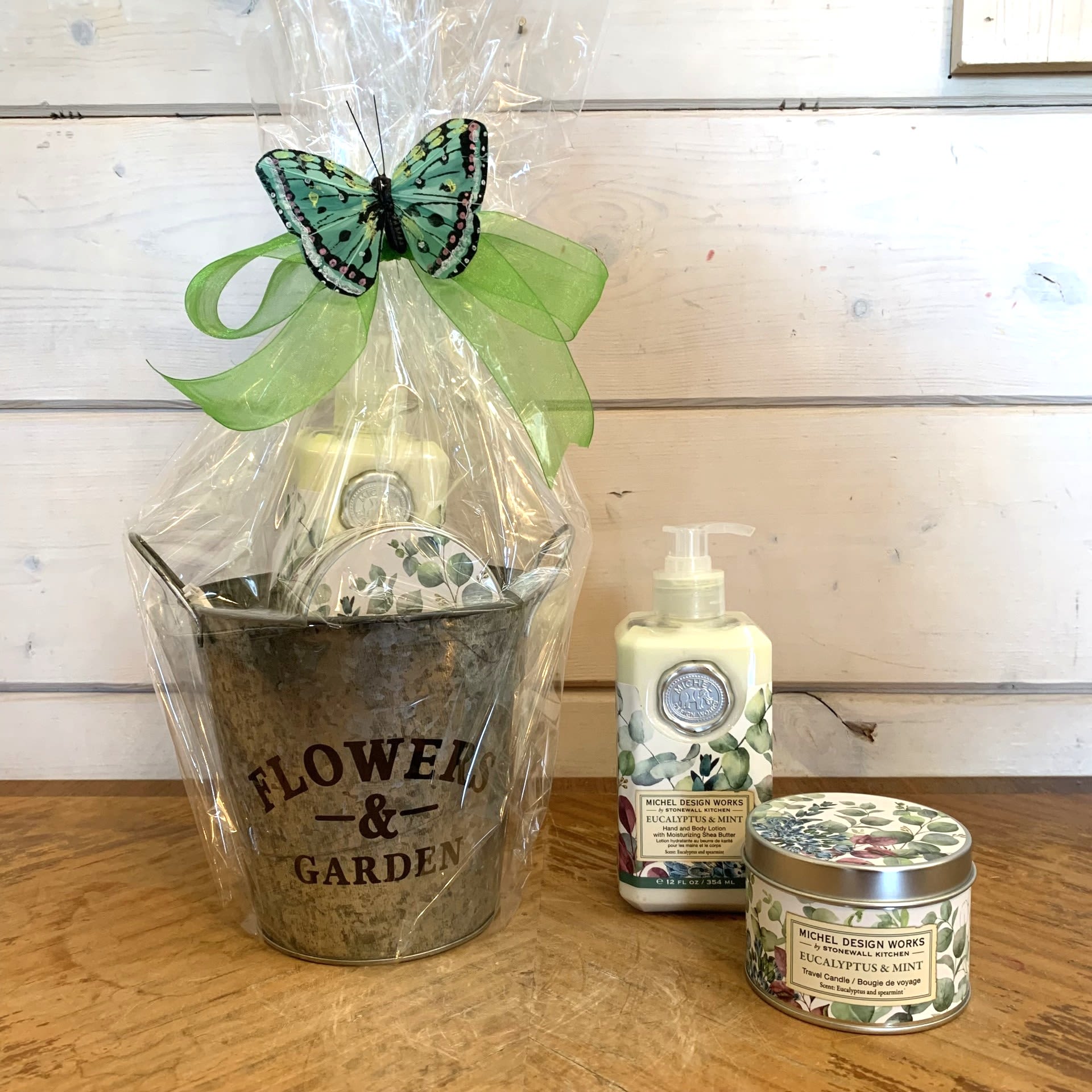 Eucalyptus and Mint Petite Gift Basket - This petite gift basket includes one hand and body lotion and one scented travel candle beautifully wrapped up and ready to go with a large bow and sweet butterfly accent.  Relax at home with the peaceful scent of eucalyptus and spearmint. Soft greens with a touch of purple brings this beautiful design to life.  Items included: 1) Our hand and body lotion is made with shea butter, aloe, and other botanical ingredients and packaged in a decorative pump bottle.  12 fl. oz. / 354 ml lotion.  2) Our all-natural, travel candle is nontoxic, biodegradable and clean burning, made from a sustainably sourced soy and palm oil wax blend. The handy, decorative, and versatile tin can be used at home or when traveling, indoors or out.  5.5 oz./ 155 g. Over 20 hrs. approximate burn time.  Fragrance: Eucalyptus and spearmint with drops of orange and geranium.  Customizable gift baskets available upon request. Please give us a call at 775-348-6161 for assistance putting together the perfect aromatherapy basket for your loved one.