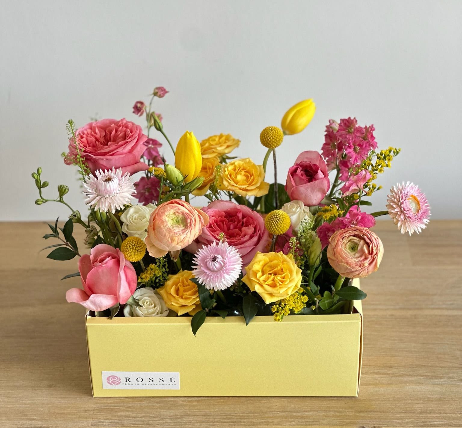 Lemonade Garden  - A yellow rectangular box filled with coral, pink, white, and yellow flowers.   Flower types may vary depending on the season.