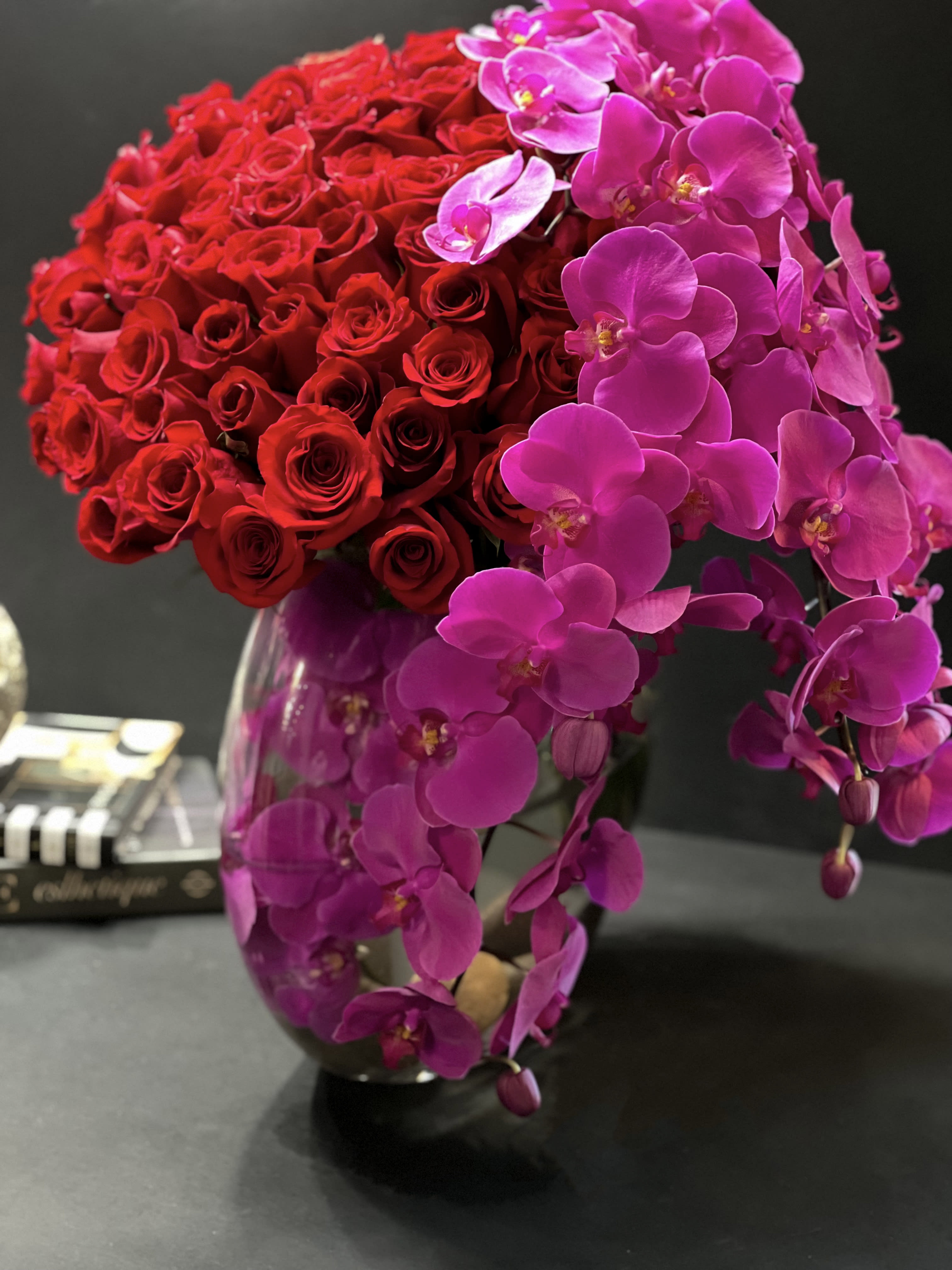 Love Waterfall  - Contemporary design with red roses and phalaenopsis orchids in vase with 75 red roses and 6-7 stems of fuchsia orchids in modern vase 