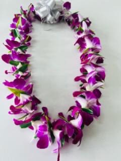 Fresh Purple Orchid Lei  - An orchid lei symbolizes aloha, royalty, love, beauty, and refinement. It is a popular choice for graduation, birthday, anniversary, weddings and any other special occasions, representing affection, congratulations, and well wishes. Orchids are chosen for their delicate petals, vibrant colors, and long-lasting blooms, making them a cherished keepsake. Green leaves are added in between each orchids to hold the lei together and to show royalty.