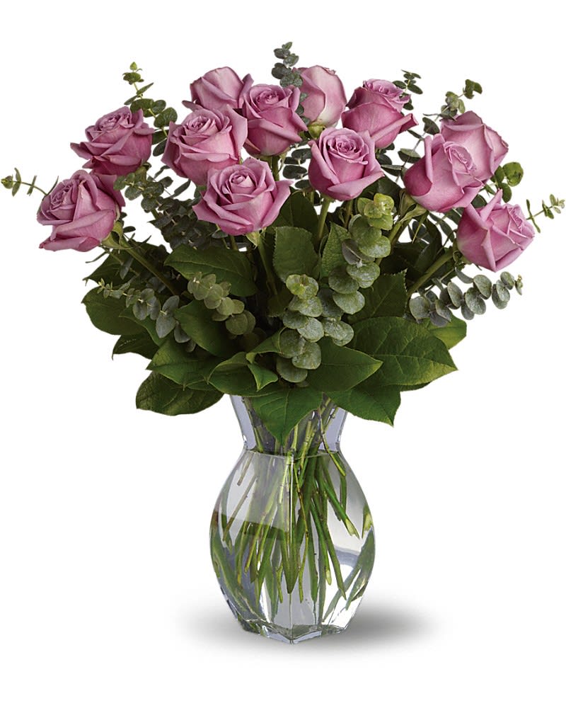 Lavender Wishes - Dozen Premium Lavender Roses - Lovely lavender roses are enchanting and exotic. They can even signify love at first sight, and when this pretty bouquet is delivered it will surely be love. Gorgeous as the roses are by themselves, when mixed with the dark forest green of eucalyptus the effect is intoxicating. Twelve delightful lavender roses, eucalyptus and greens are delivered in a similar clear glass vase. It's a wish come true!Approximately 20&quot; W x 21&quot; H