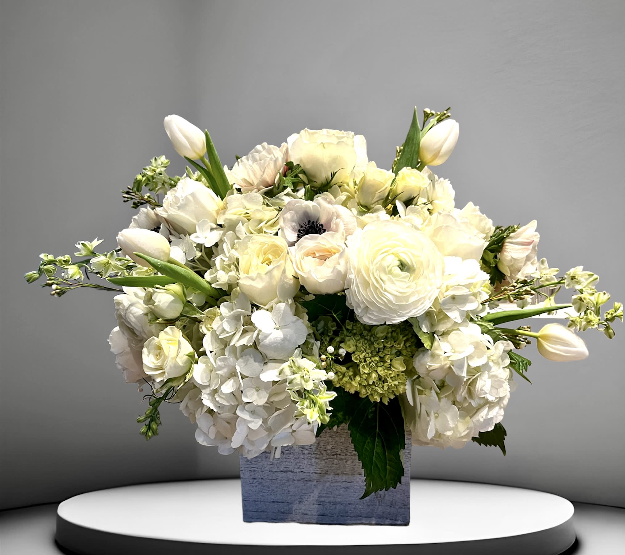 Dreamy - A dreamy white arrangement of hydrangea, roses, and other seasonal flowers arranged in a large birch wood planter. A perfect way to express sympathy or make a statement in the home.